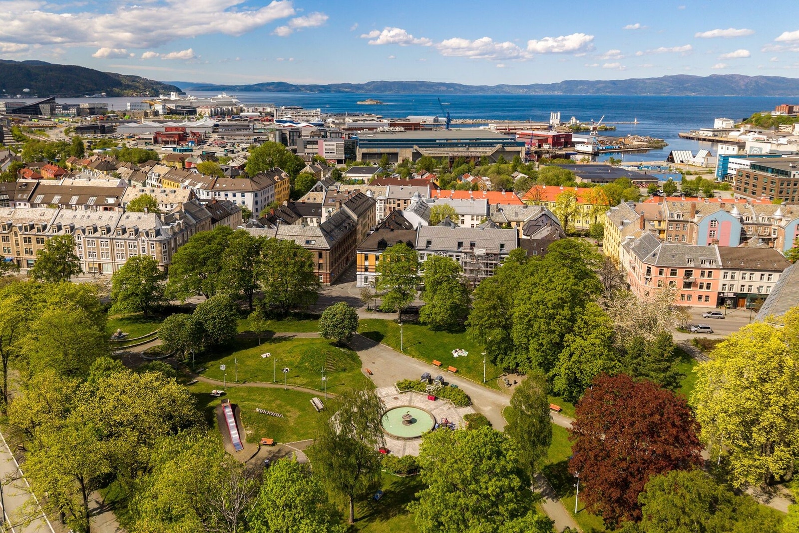 Lademoparken med lekeplass, fontene og benker befinner seg på andre siden av veien Galleribilde