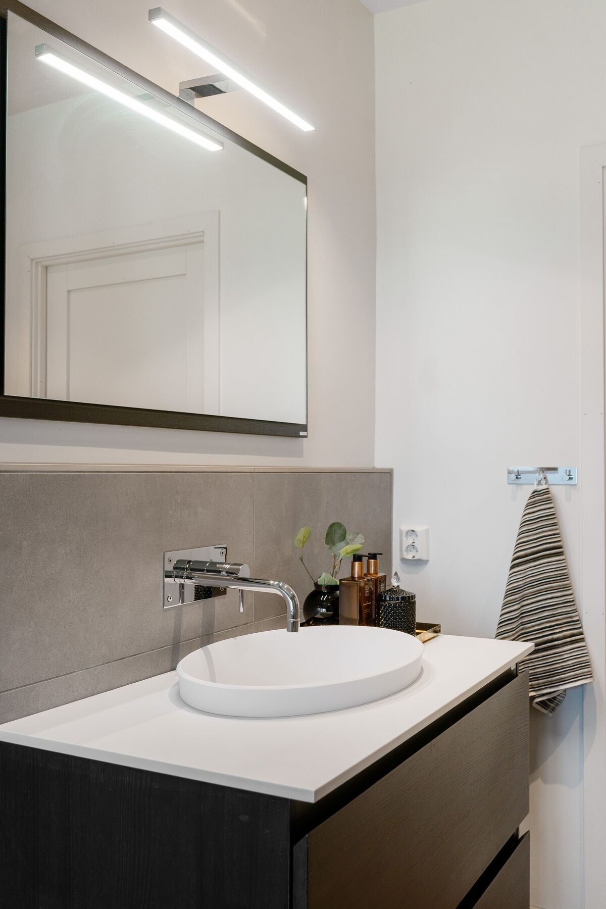 Badet er utstyrt med stilsikker baderomsinnredning, vegghengt toalett, dusjvegg av glass og multifunksjonsdusj med mange ulike spylemuligheter. Galleribilde