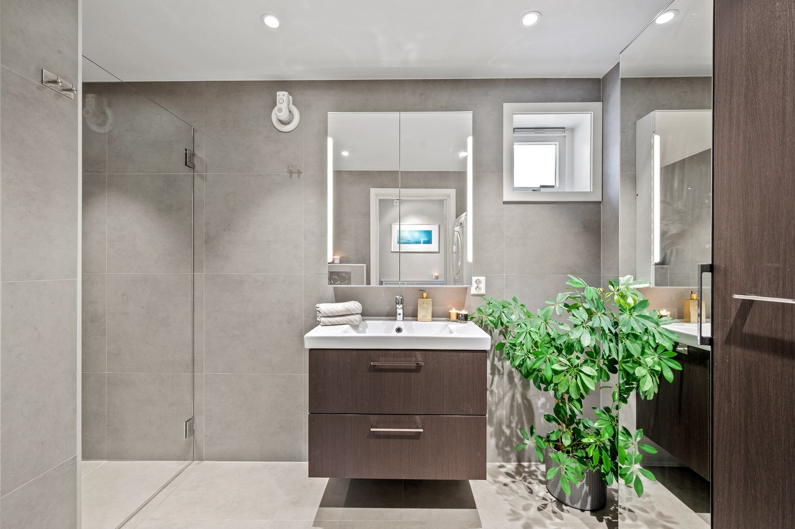 Badet er innredet med bl.a veggmontert WC, dusjnisje, servant på underskap, veggskap, speilskap og varme i gulv. Galleribilde