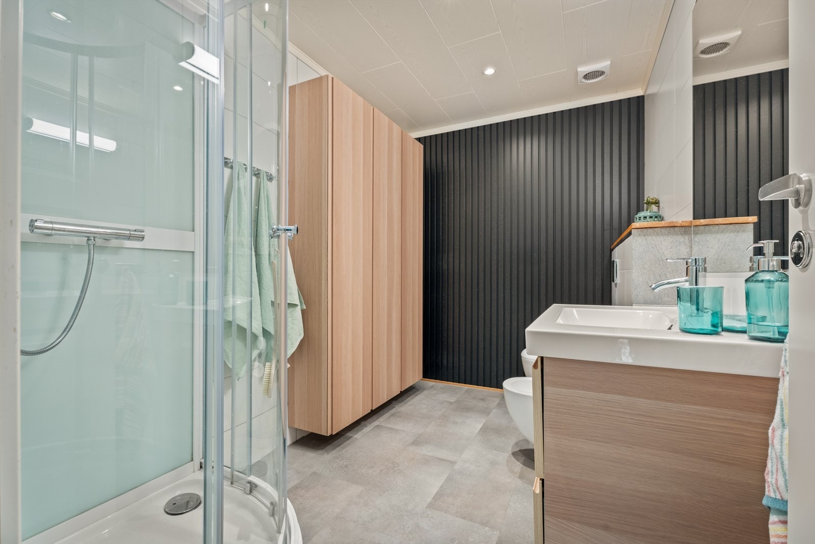 Badet er innredet med servant, vegghengt toalett, bidé og dusjkabinett. Galleribilde