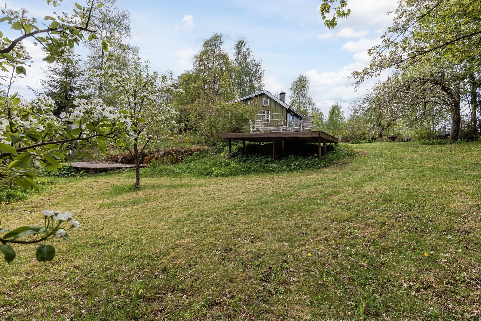 Eiendommen ligger på en hyggelig og pent opparbeidet tomt som harmonerer flott med de naturskjønne omgivelsene. Tomten består av velholdte gressplener, prydbusker og naturlige vegetasjonsområder som gir eiendommen et grønt og innbydende preg. Galleribilde