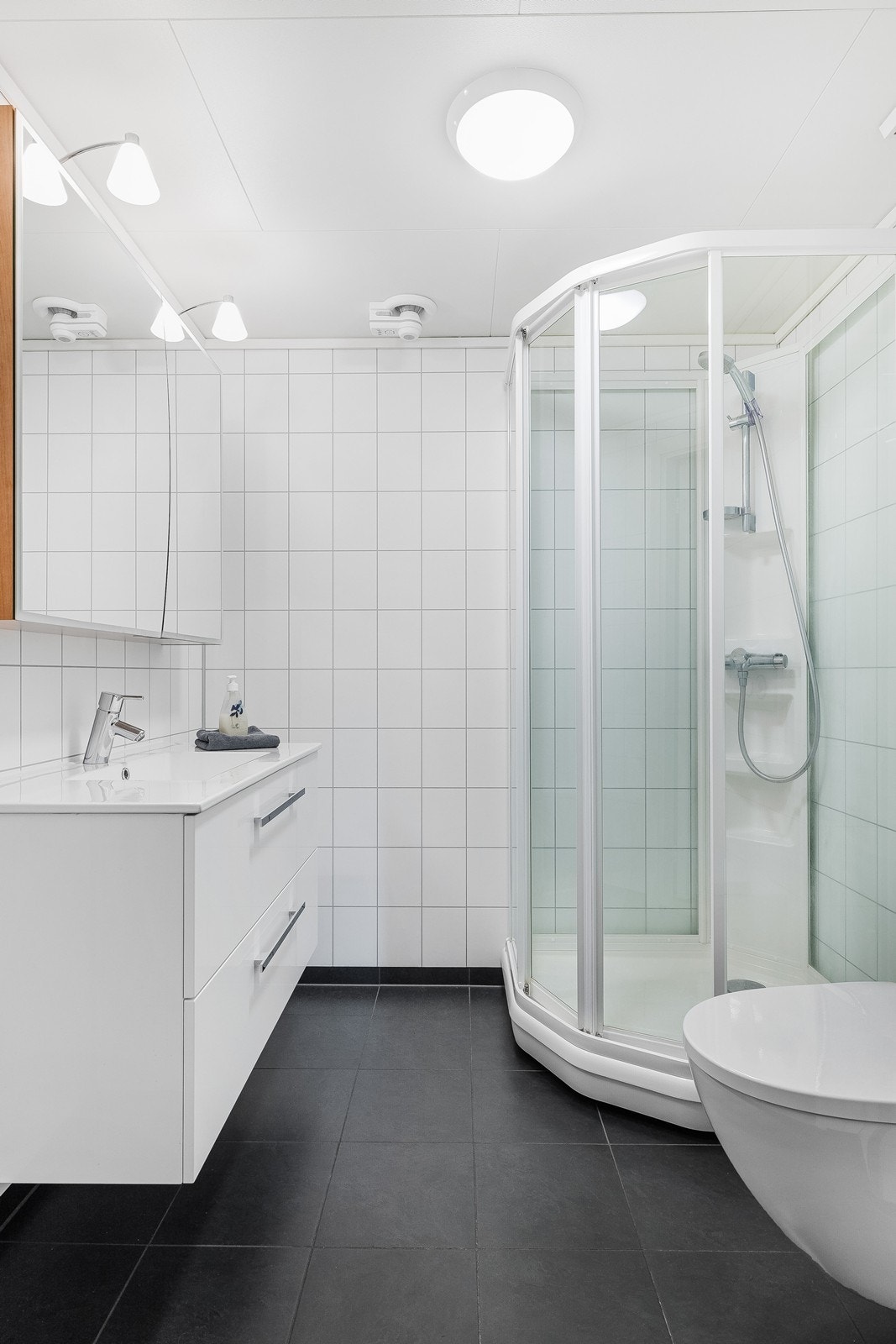 Stilrent baderom med lys innredning, fliser på gulv og våtromsplater på vegg. Galleribilde