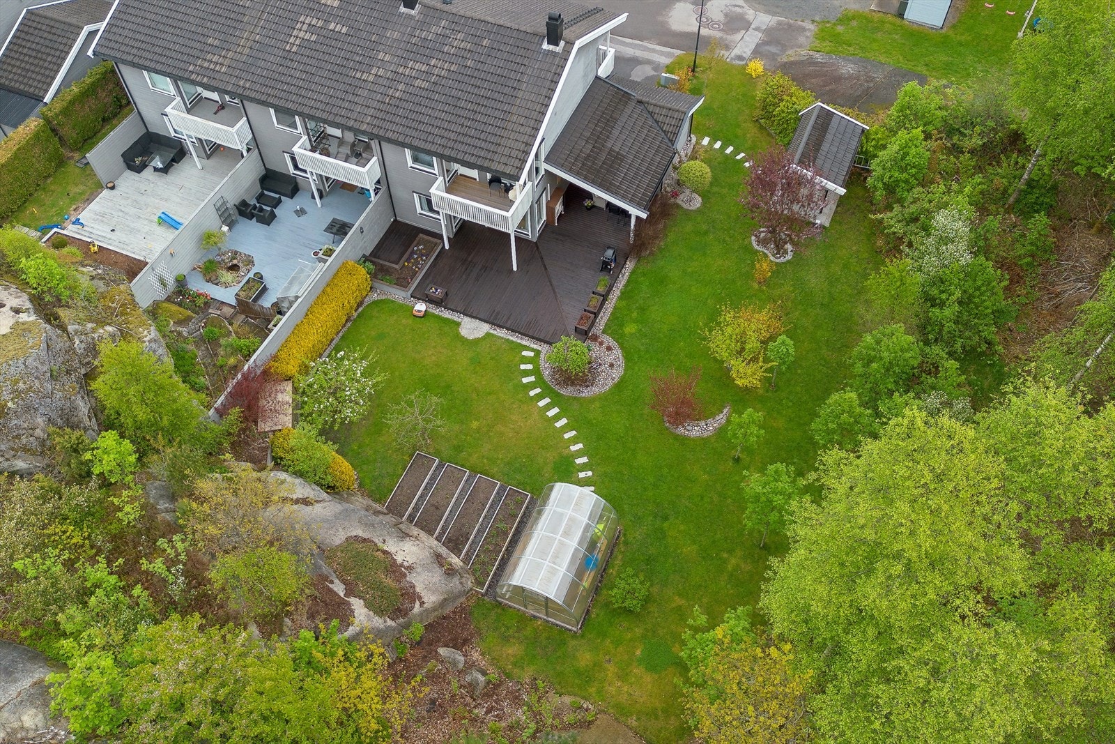 Oversikt over den romslige tomten med hage, veksthus og terrasse. Galleribilde