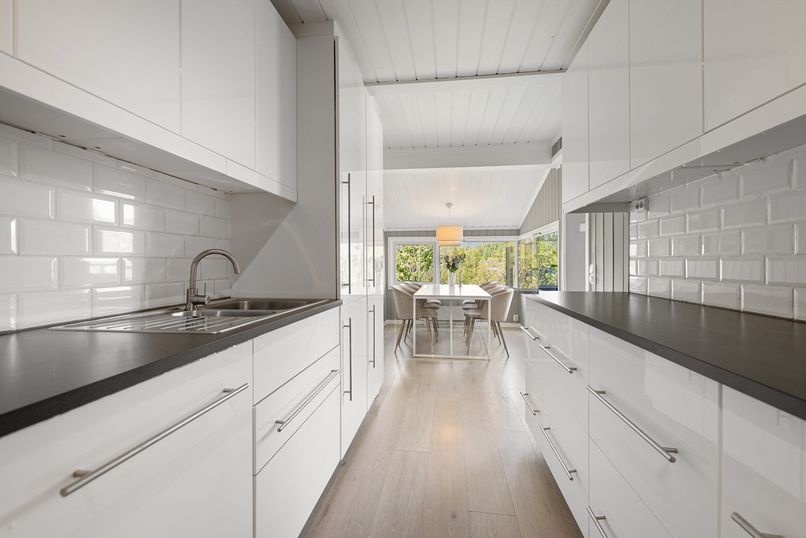 Kjøkkeninnredningen fra IKEA har glatte fronter og benkeplate i laminat med toppmontert metallvask og ettgreps kjøkkenarmatur (Byttet i 2026). Mellom benk og overskap er det fliser. Galleribilde