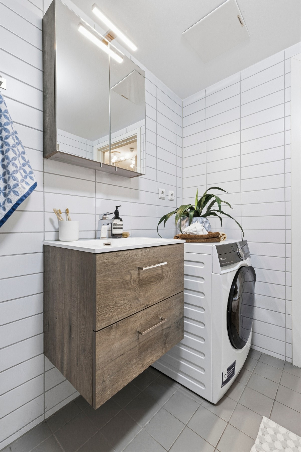 Badet er innredet med servant, vegghengt toalett, dusjhjørne med dusjvegger samt opplegg for vaskemaskin. Galleribilde
