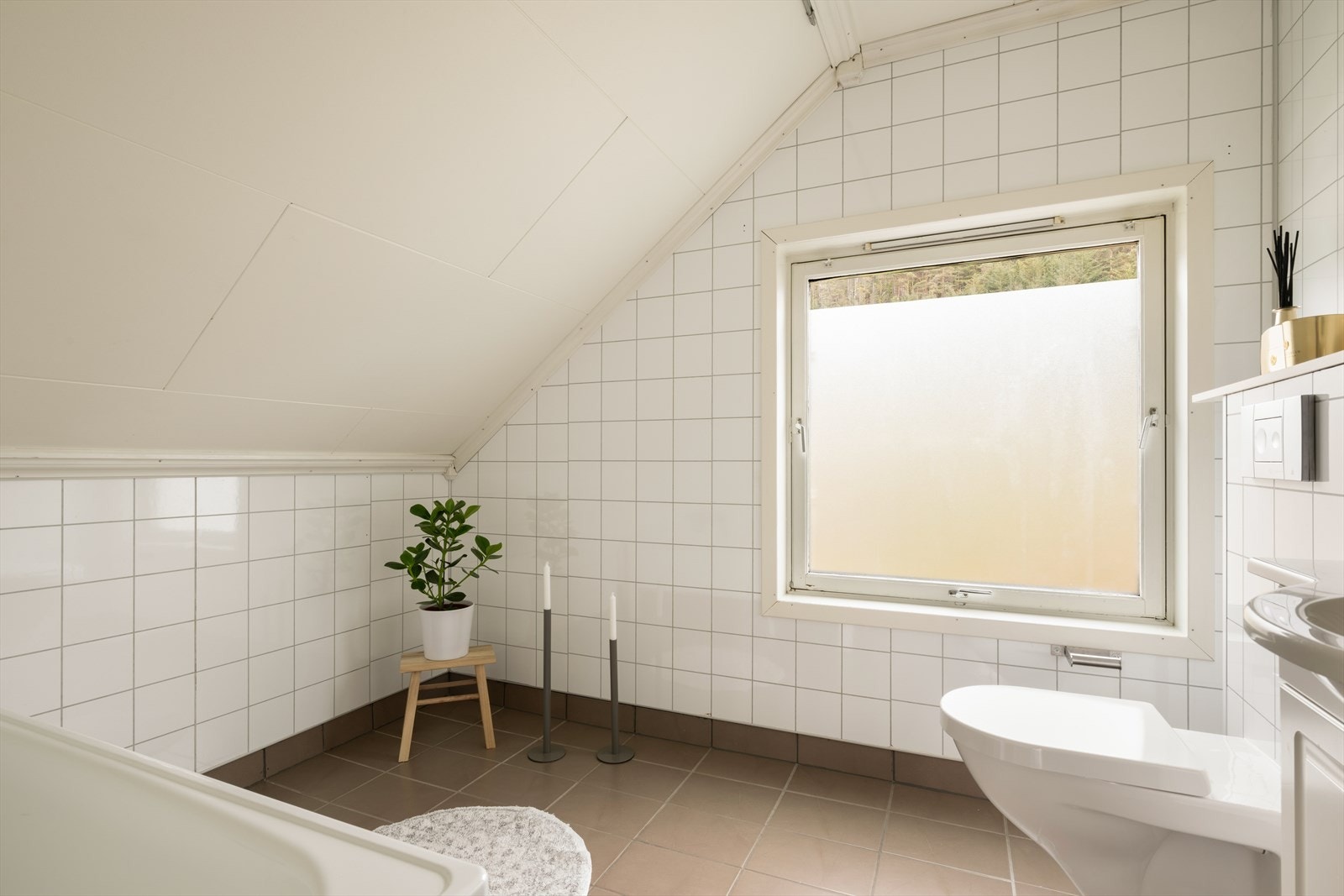 Badet er innredet med vegghengt toalett, skapseksjon med servant og badekar. Galleribilde