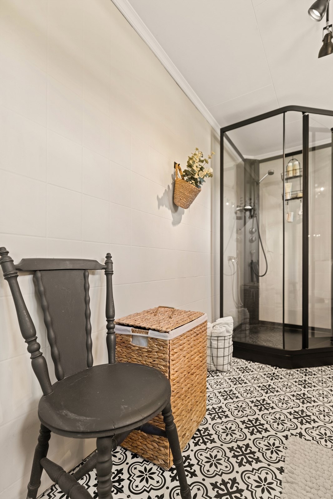 Badet har mønstrede gulvfliser og dusjkabinett med sorte profiler. Galleribilde