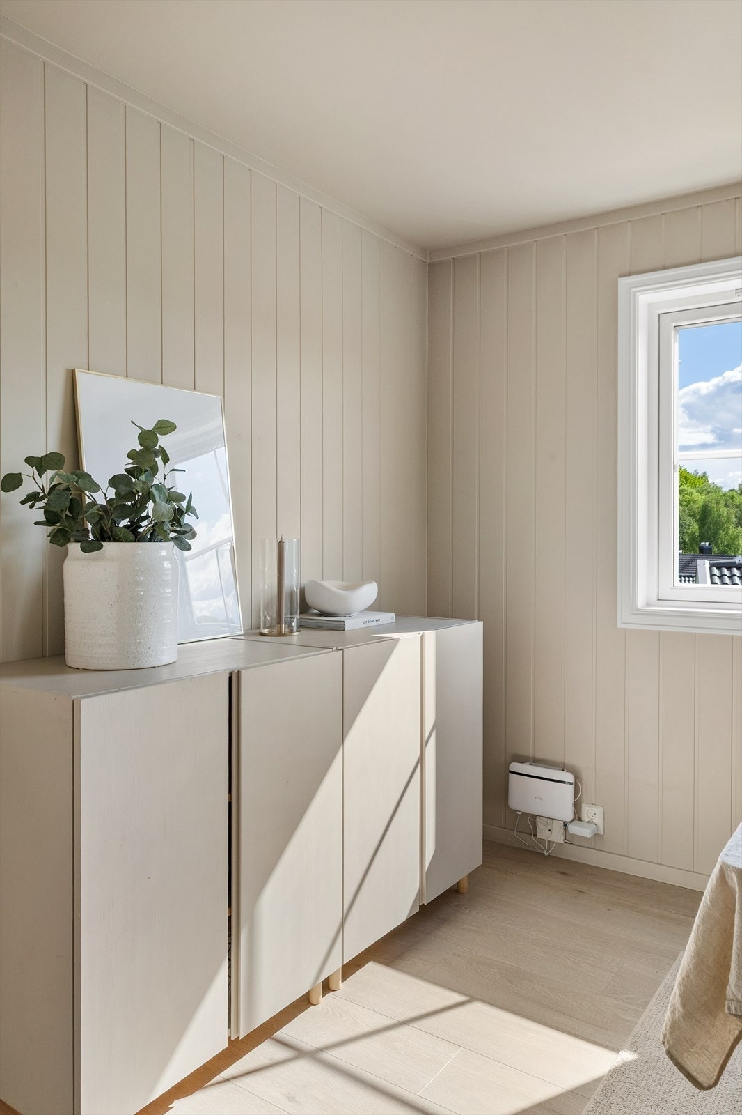 Glatte, malte veggflater og laminat på gulvet gir et lyst og helhetlig inntrykk. Galleribilde