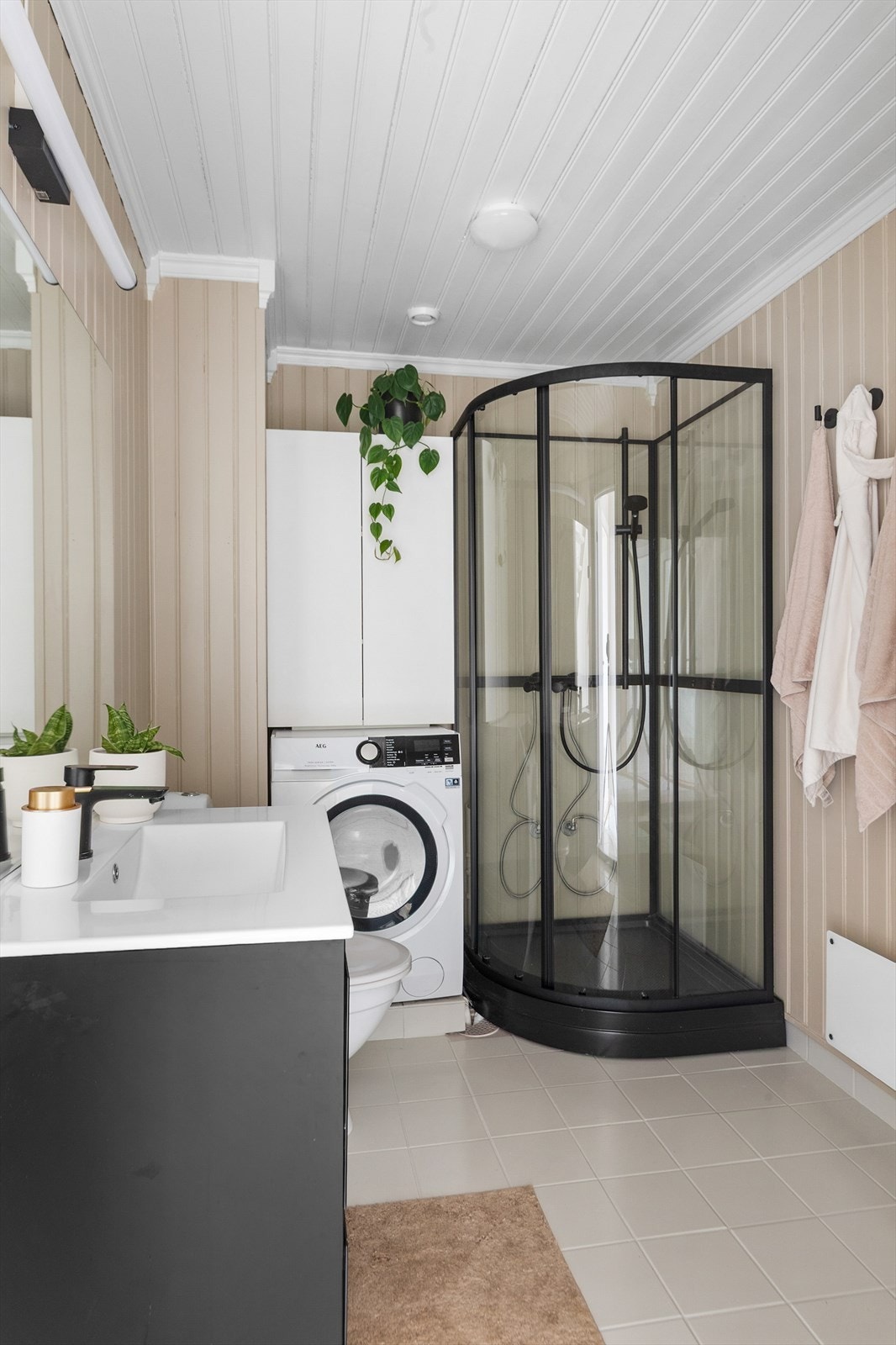 Badet i første etasje har flislagt gulv, malt panel på veggene og opplegg for vaskemaskin. Galleribilde