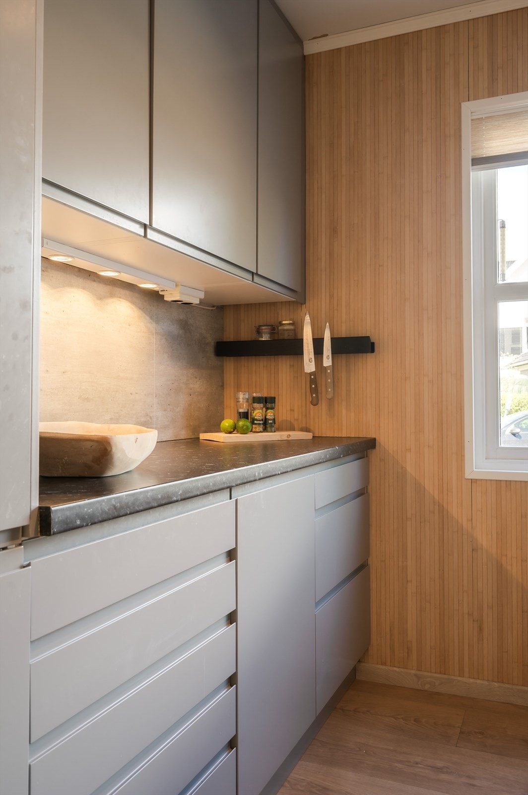 Innredningen har glatte fronter og laminert benkeplate med nedfelt oppvaskkum. Praktisk med belysning under de takhøye overskapene. Galleribilde