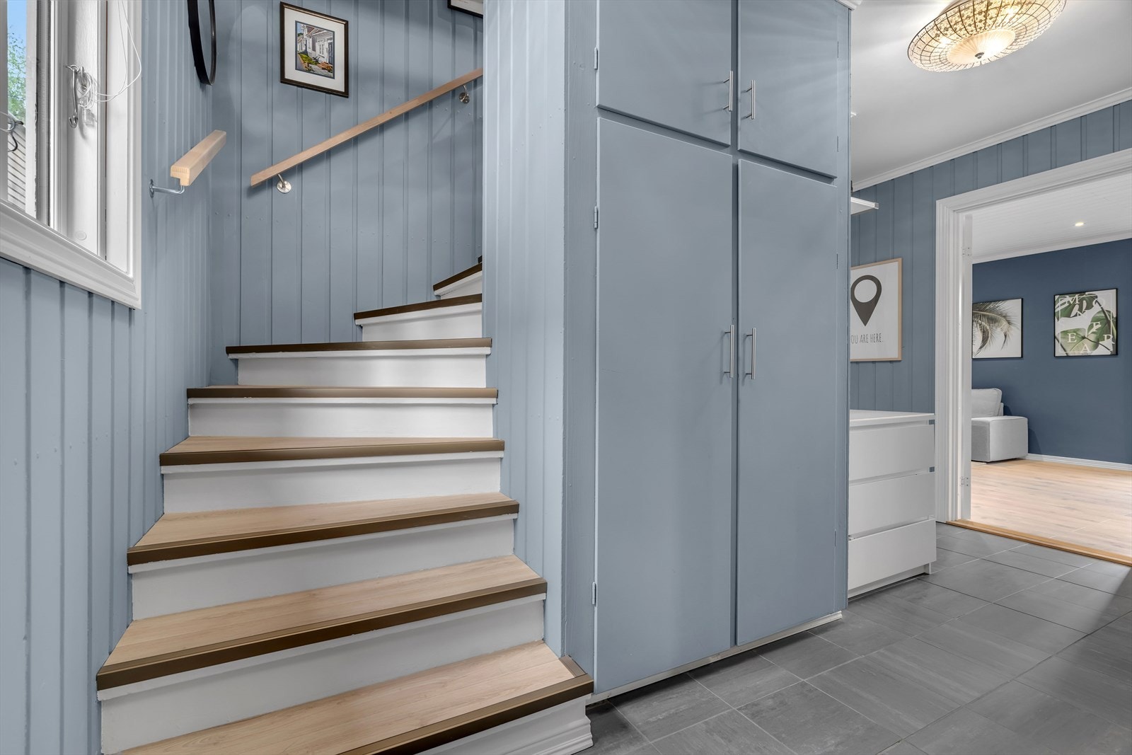 Fra entréen fører trappen opp til 2. etasje, og åpningen inn til stuen gir umiddelbart innblikk i boligens store oppholdsrom. Galleribilde