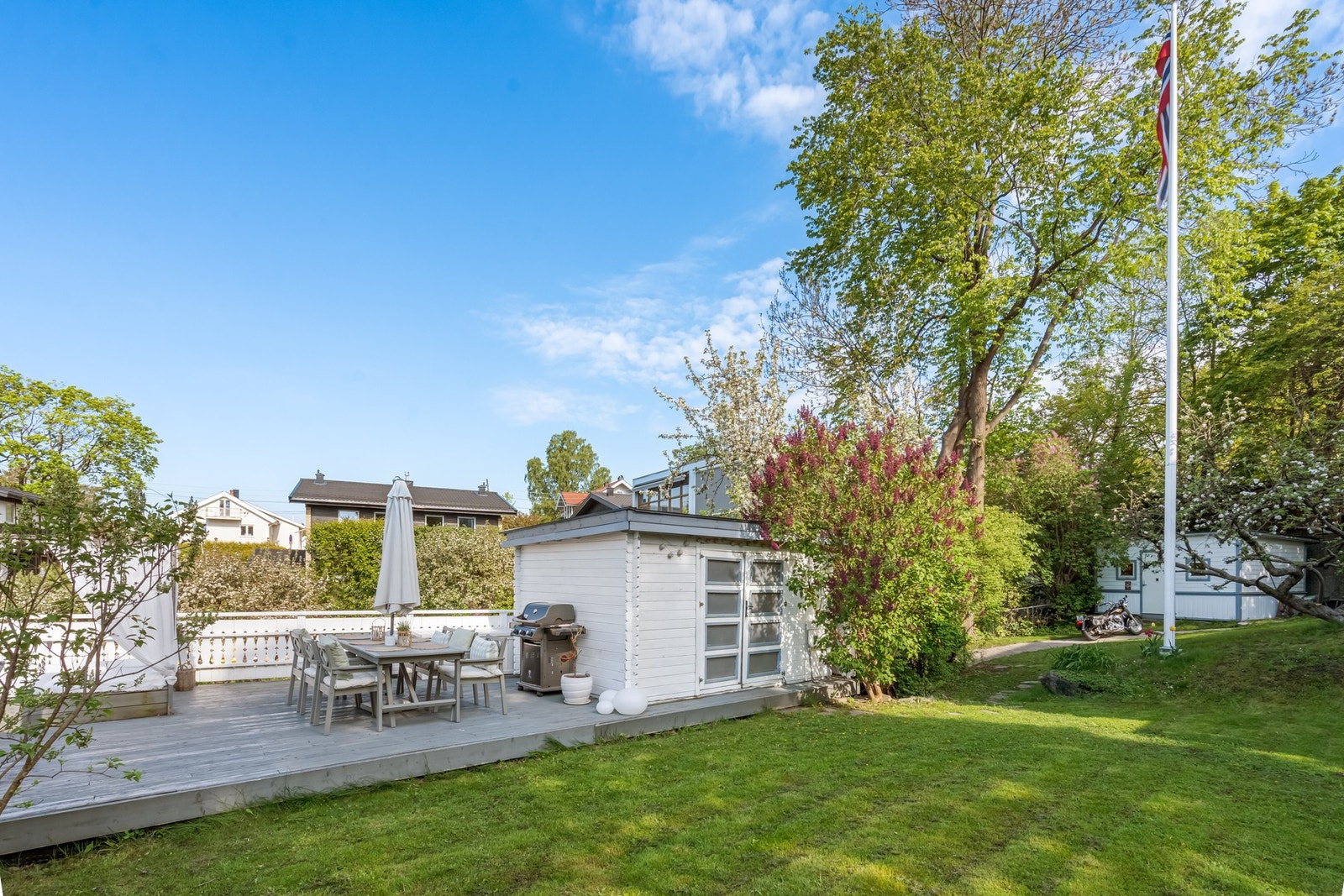 Terrasse og hage. Det er satt opp to utvendige bygninger på tomten. Utvendig bod og uthus. Galleribilde