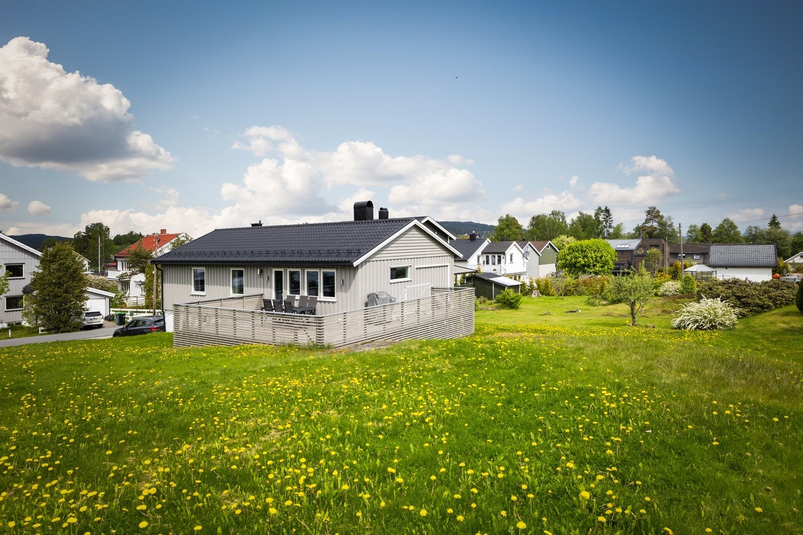 Boligen ligger tilbaketrukket fra hovedveien, med en stor gressplen foran huset. Galleribilde