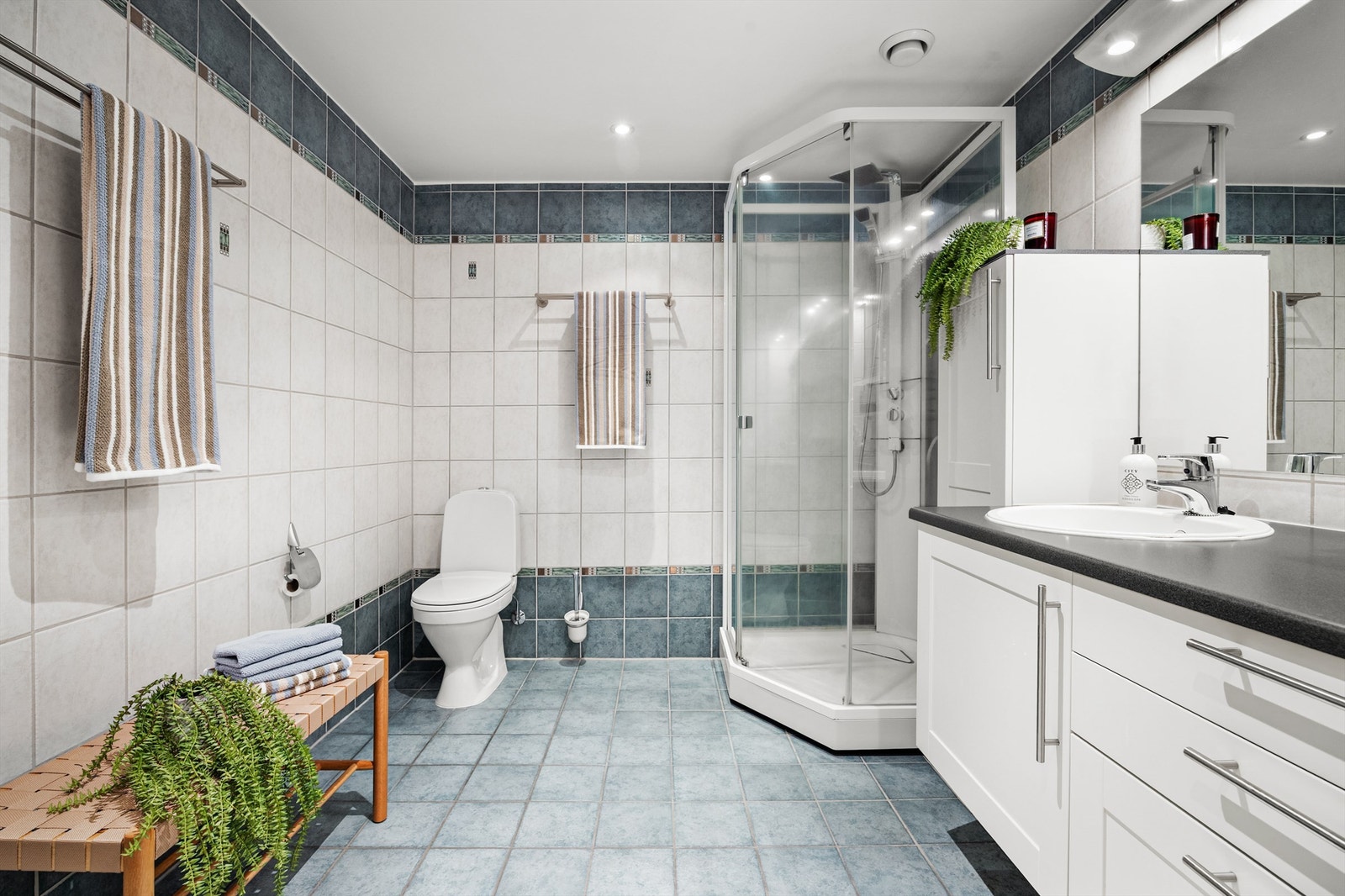 Badet er fra byggeåret og har flislagt gulv med varmekabler, dusjkabinett og downlights i himlingen. Galleribilde
