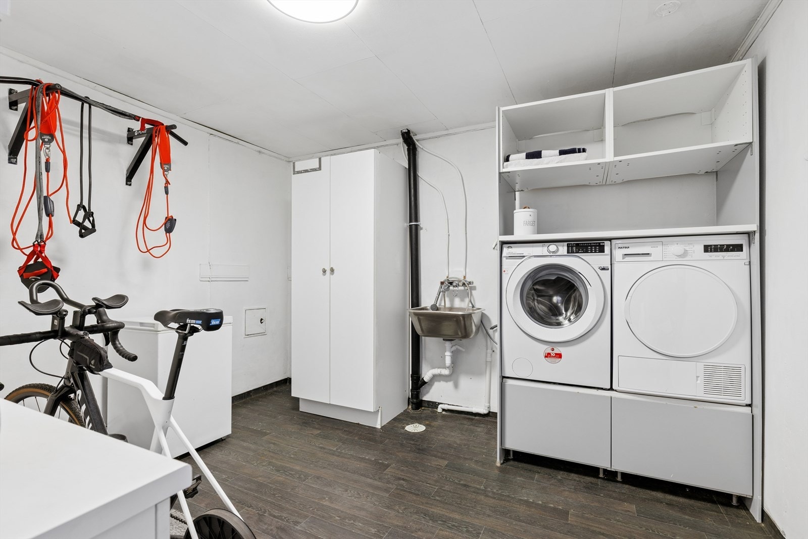 Praktisk bod i underetasjen innredet som vaskerom med belegg på gulv, utslagsvask og god plass til oppbevaring. Galleribilde