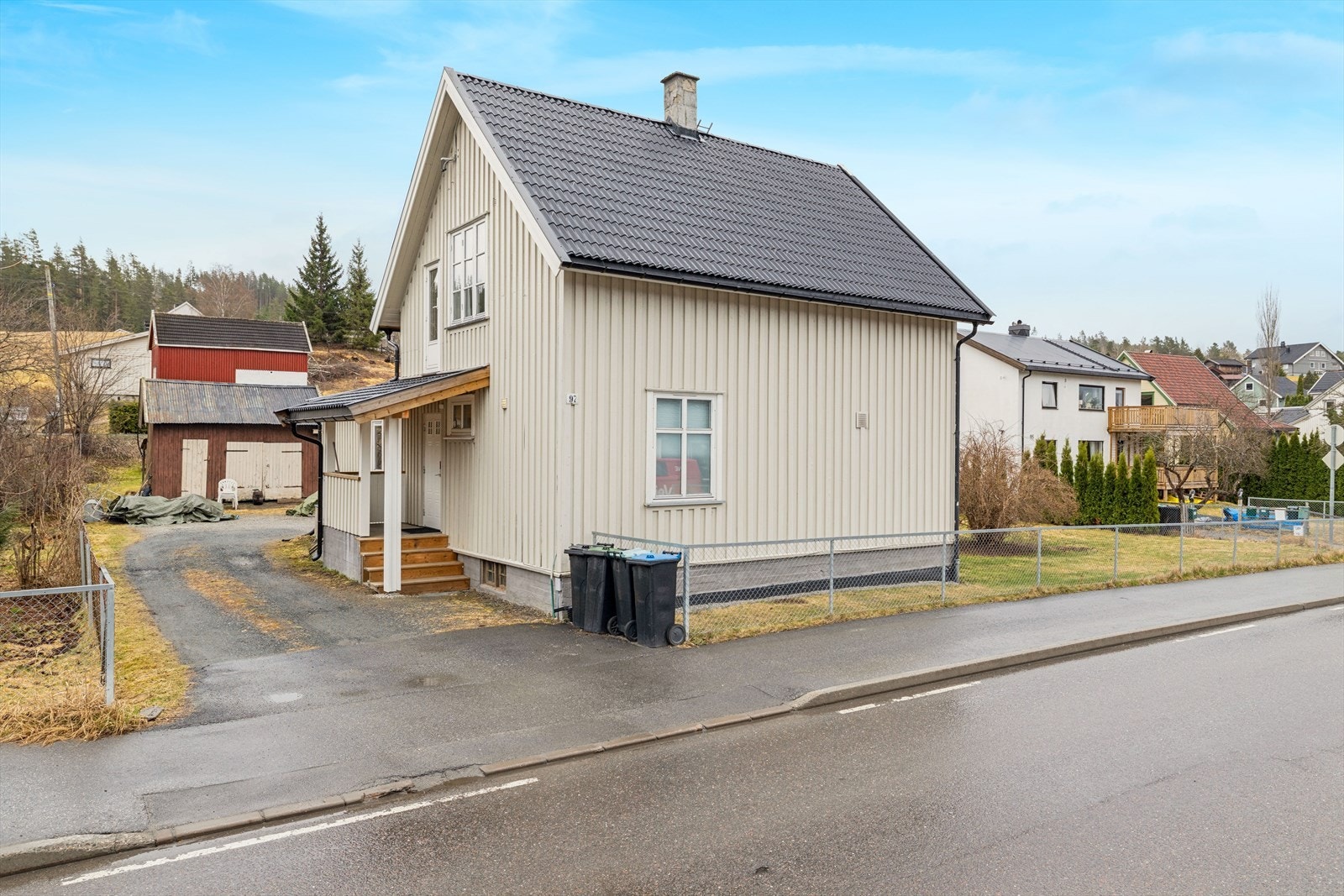 Klassisk enebolig med stående bordkledning og overbygget inngangsparti. Galleribilde