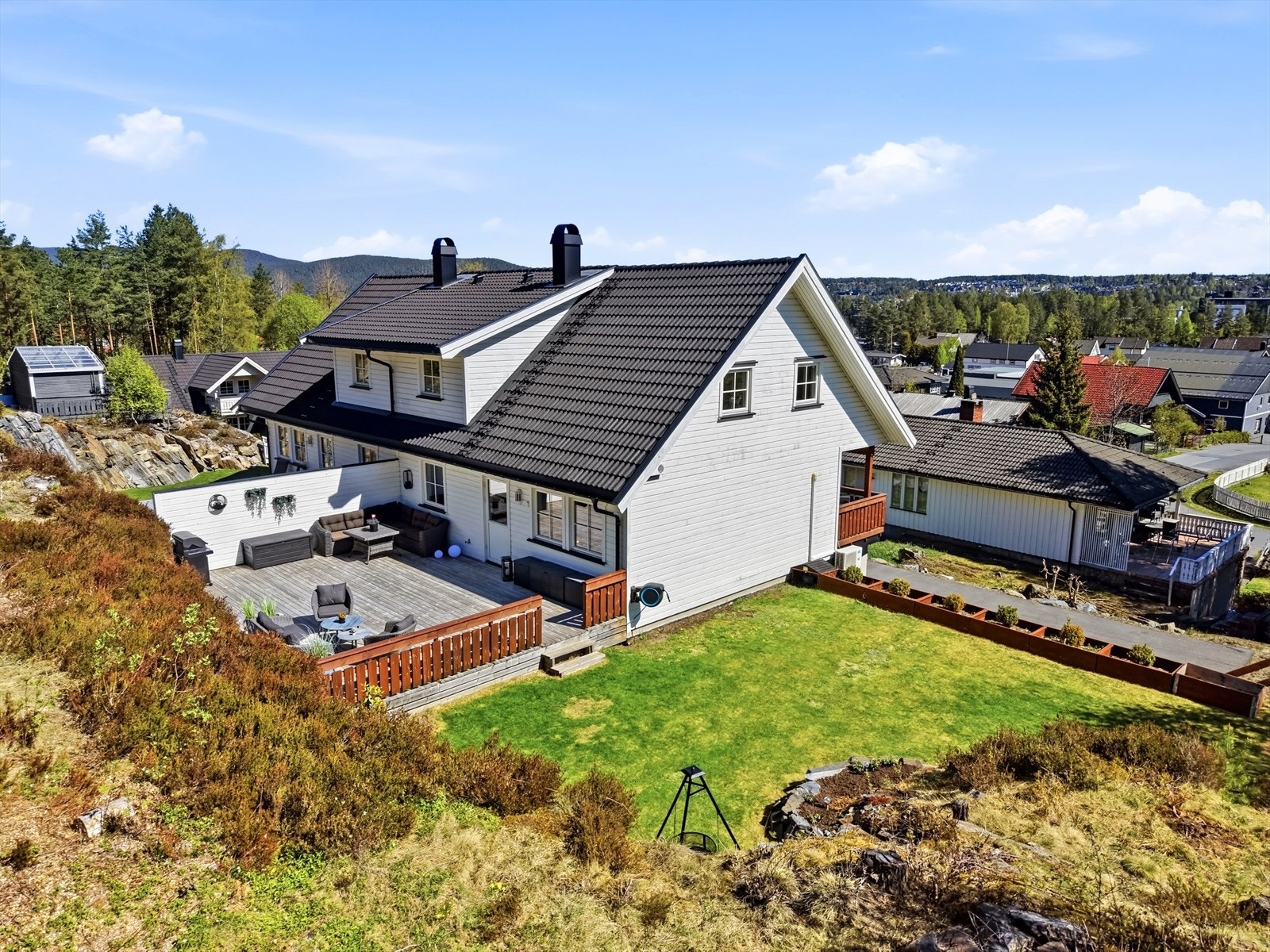Tomta utvendig er pent opparbeidet med plen og støttemurer. Mot trappa og parkeringsområdet er det satt opp plantekasser, som lager en naturlig avgrensning mot skråningen ned mot inngangspartiet. Galleribilde