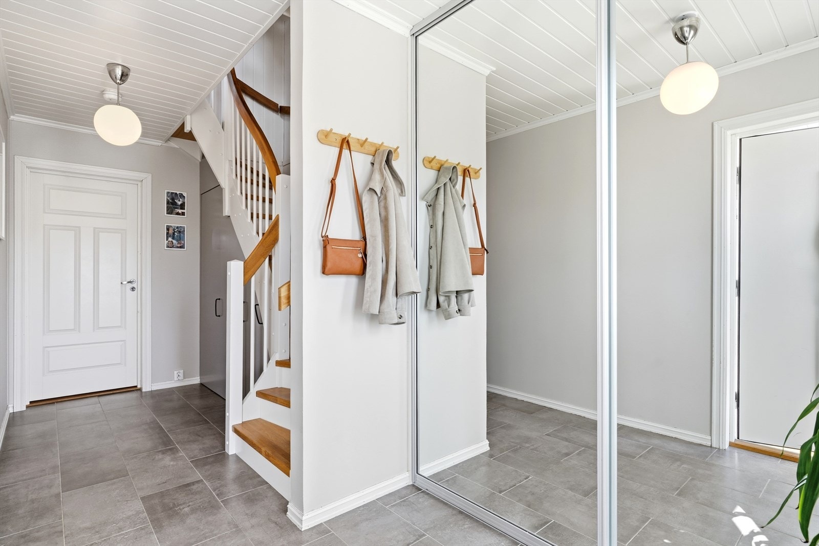 Fra hallen fører trappen deg videre opp til boligens hovedetasje, og i plassbygd løsning under trappa, har selger fått møbelsnekekr til å plassbygge flotte, integrerte garderober. Galleribilde
