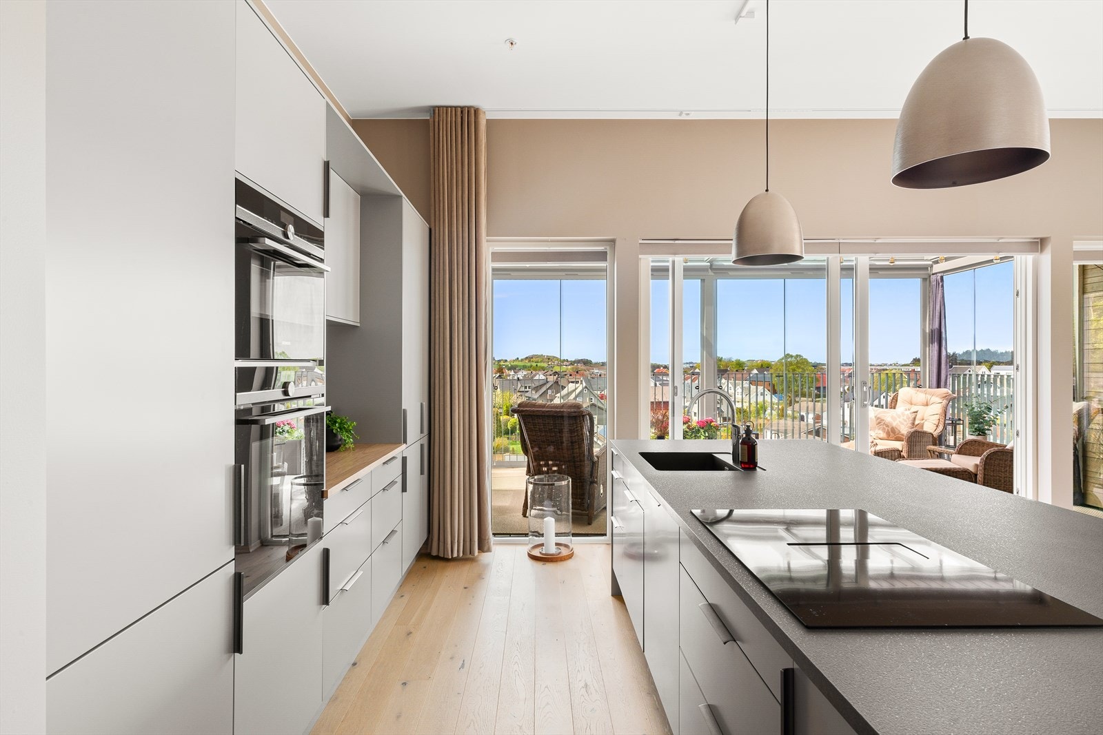 Kjøkkenet er stilrent, med slette fronter i en elegant gråtone, kjøkkenøy og rikelig med skap- og benkeplass. Galleribilde