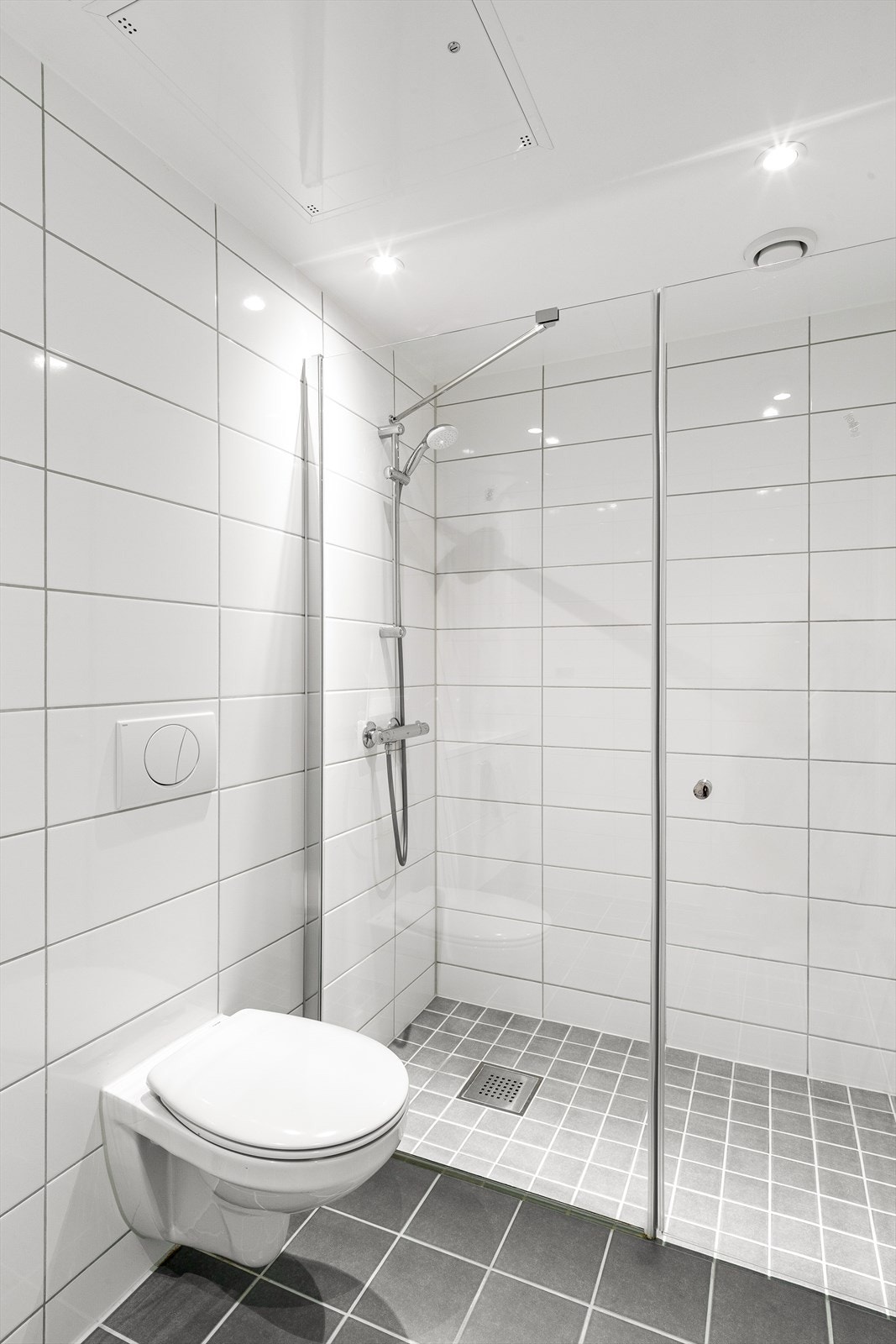 Badet er helfliset med varmekabler i gulvet og innredet med servant, vegghengt toalett og dusj med glassvegg/-dør. Galleribilde