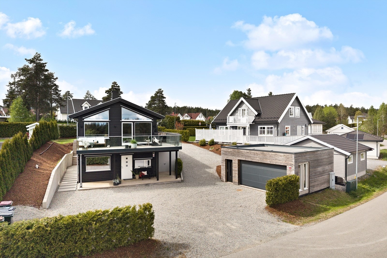 Enebolig med moderne arkitektur, store vindusflater og en separat garasje med tilhørende bod. Galleribilde