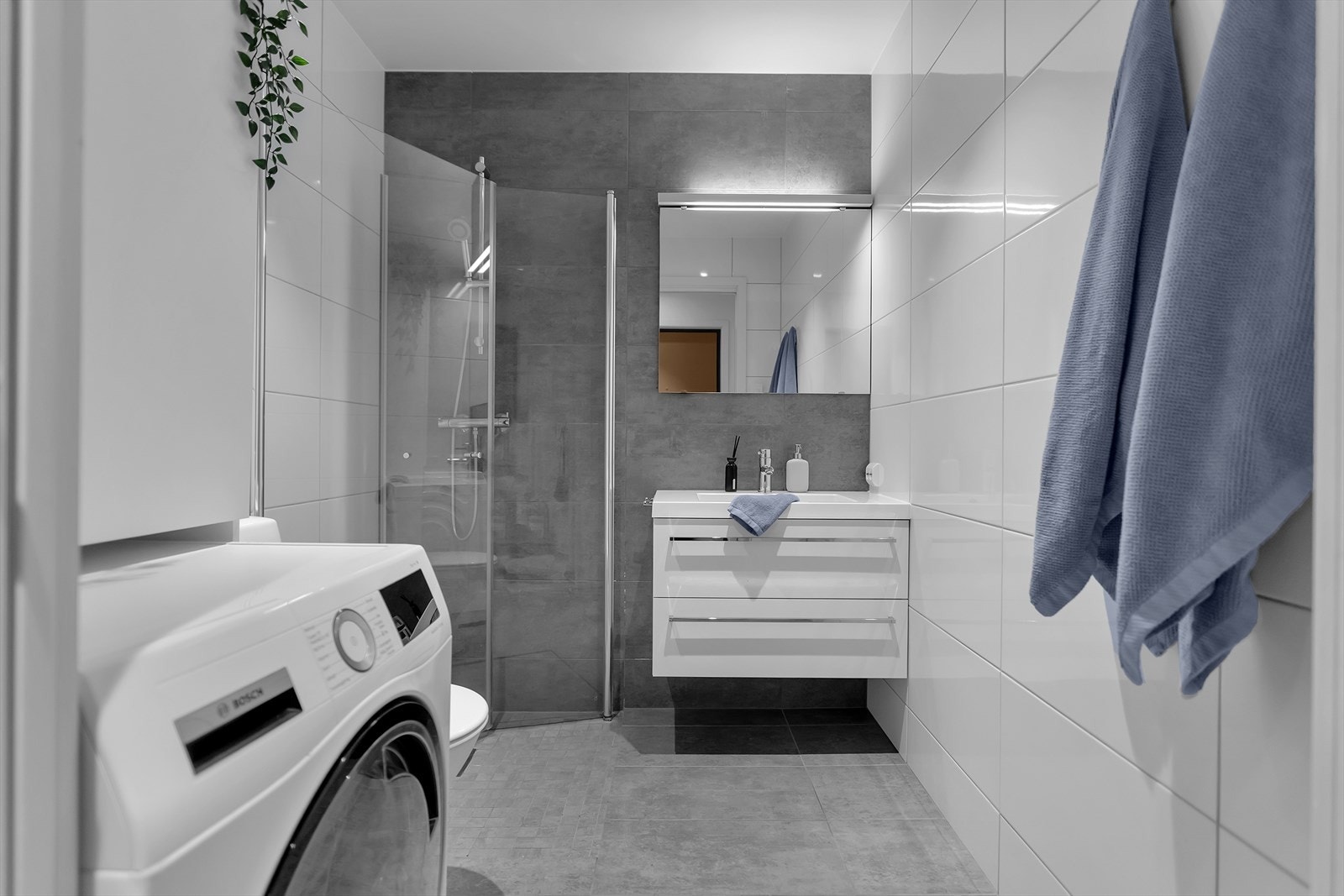 Badet har hvit innredning med heldekkende porselensvask og opplegg for vaskemaskin. Galleribilde