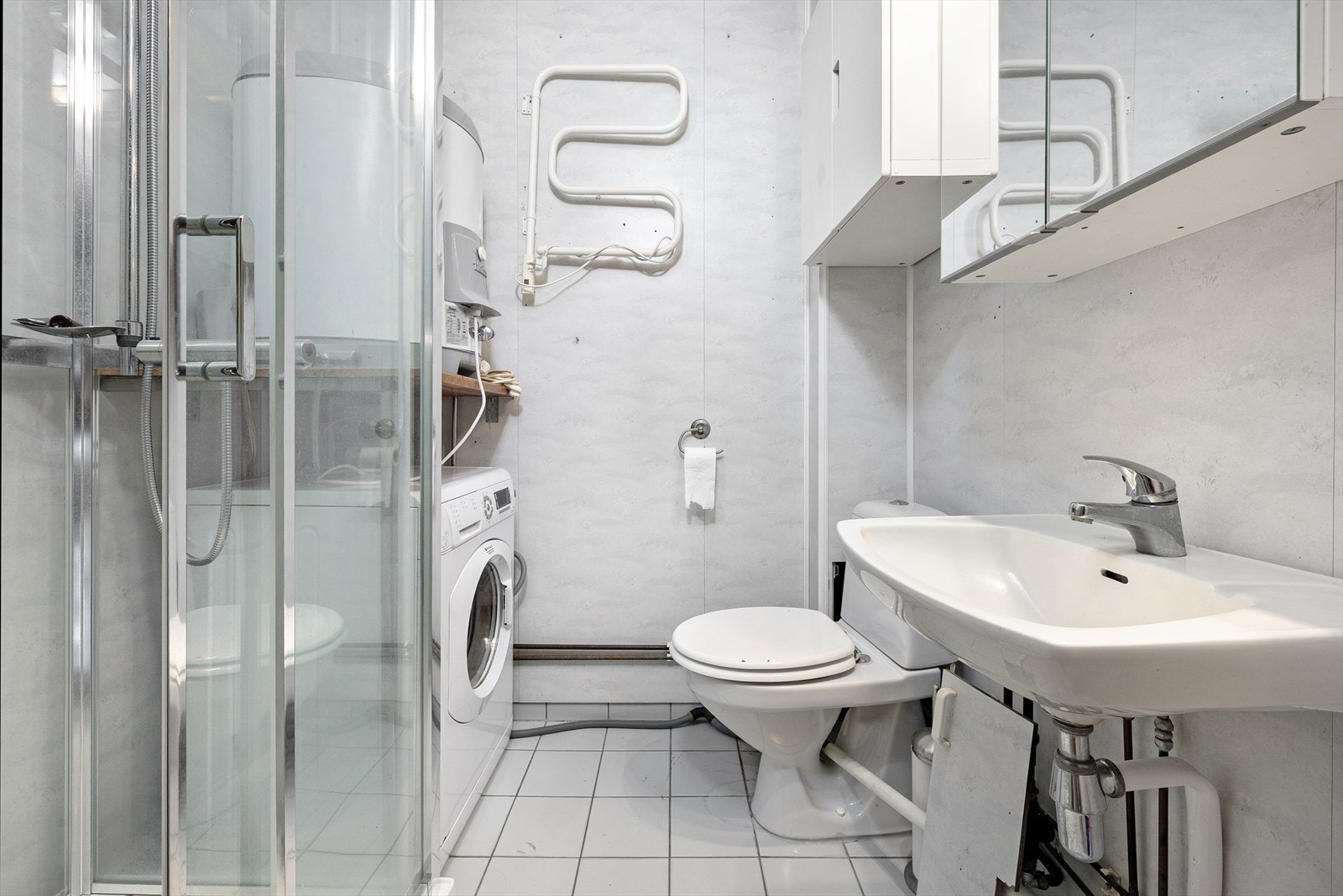 Badet har flislagt gulv med varmekabler, dusjkabinett og opplegg for vaskemaskin. Galleribilde