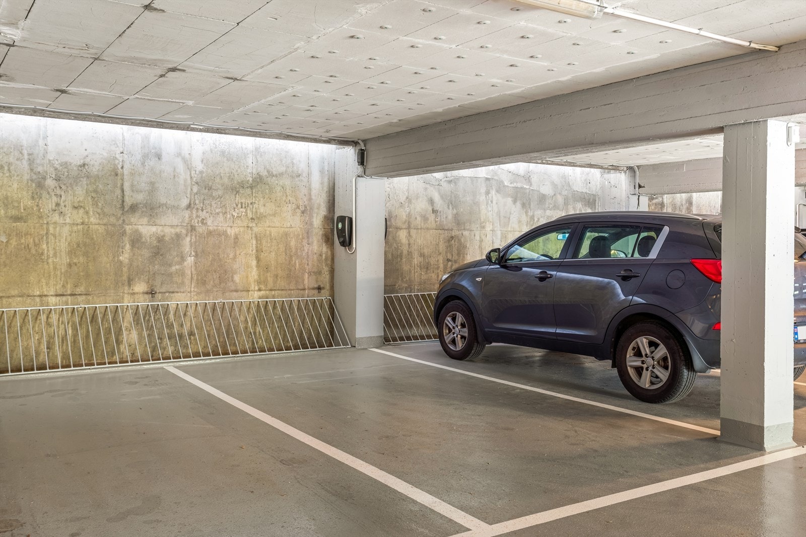 Det medfølger parkeringsplass med elbillader i nyoppusset garasjeanlegg. Gjesteparkering på garasjetaket. Bildet er tatt av en annen parkeringsplass enn den som følger boligen. Galleribilde
