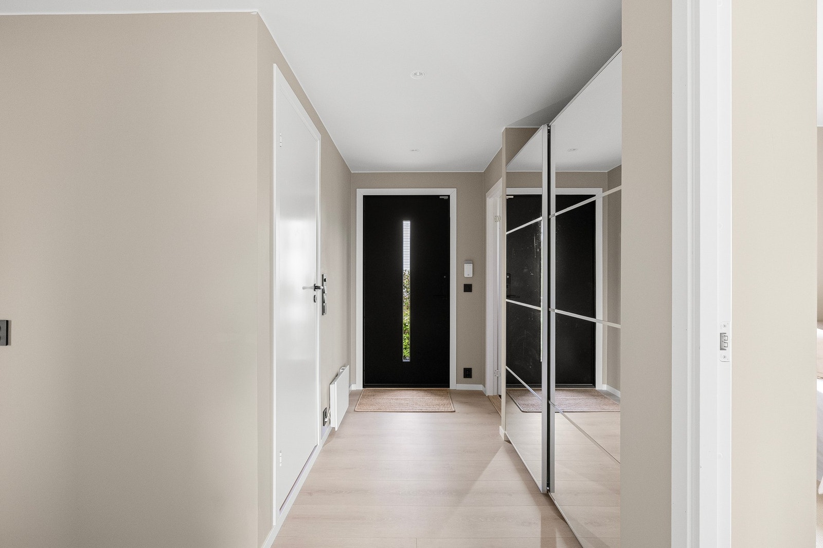 Boligen ønsker velkommen med en lys og moderne entré og gang med gjennomført fargepalett, downlights og stilrene overflater. Galleribilde