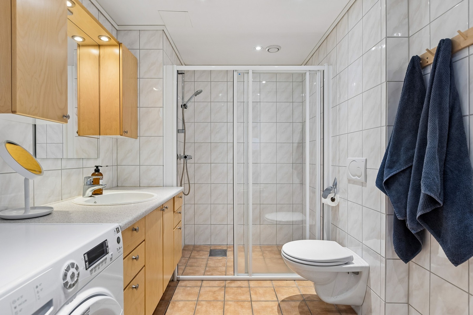 Badet er på 5 kvm og er innredet med opplegg for vaskemaskin, vegghengt toalett, servantskap og overskap med lys. Galleribilde