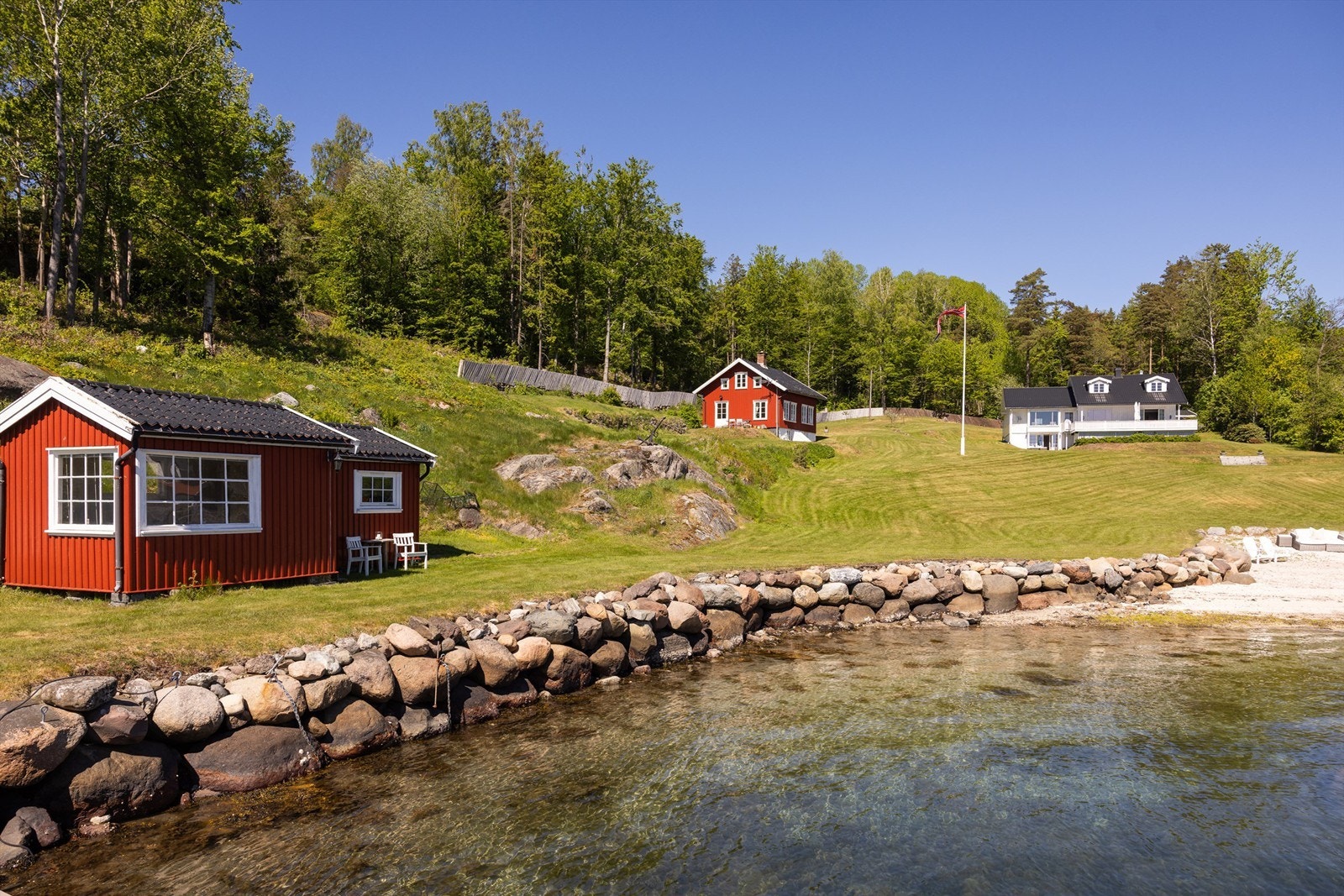 En praktfull, inngjerdet strandtomt bestående av en stor, parkmessig opparbeidet gressplen, egen lang sandstrand samt en elegant strandpromenade i stein Galleribilde