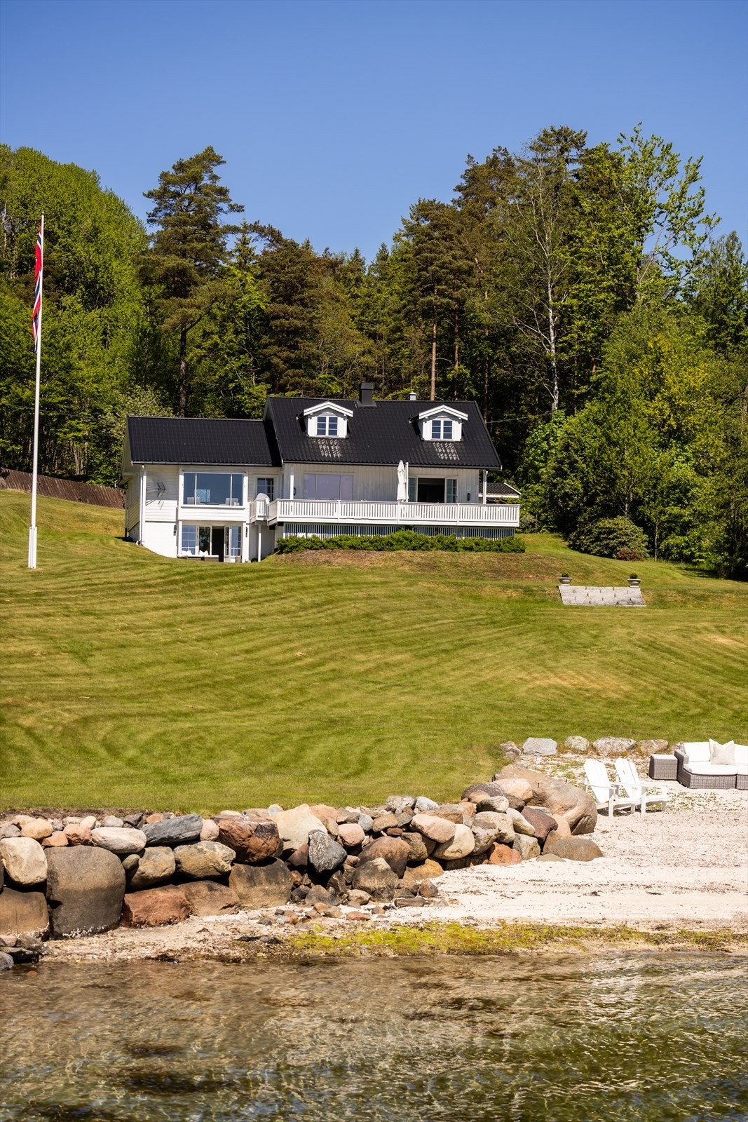 Hovedhuset ligger høyt og fritt på den skrånende tomten. Galleribilde