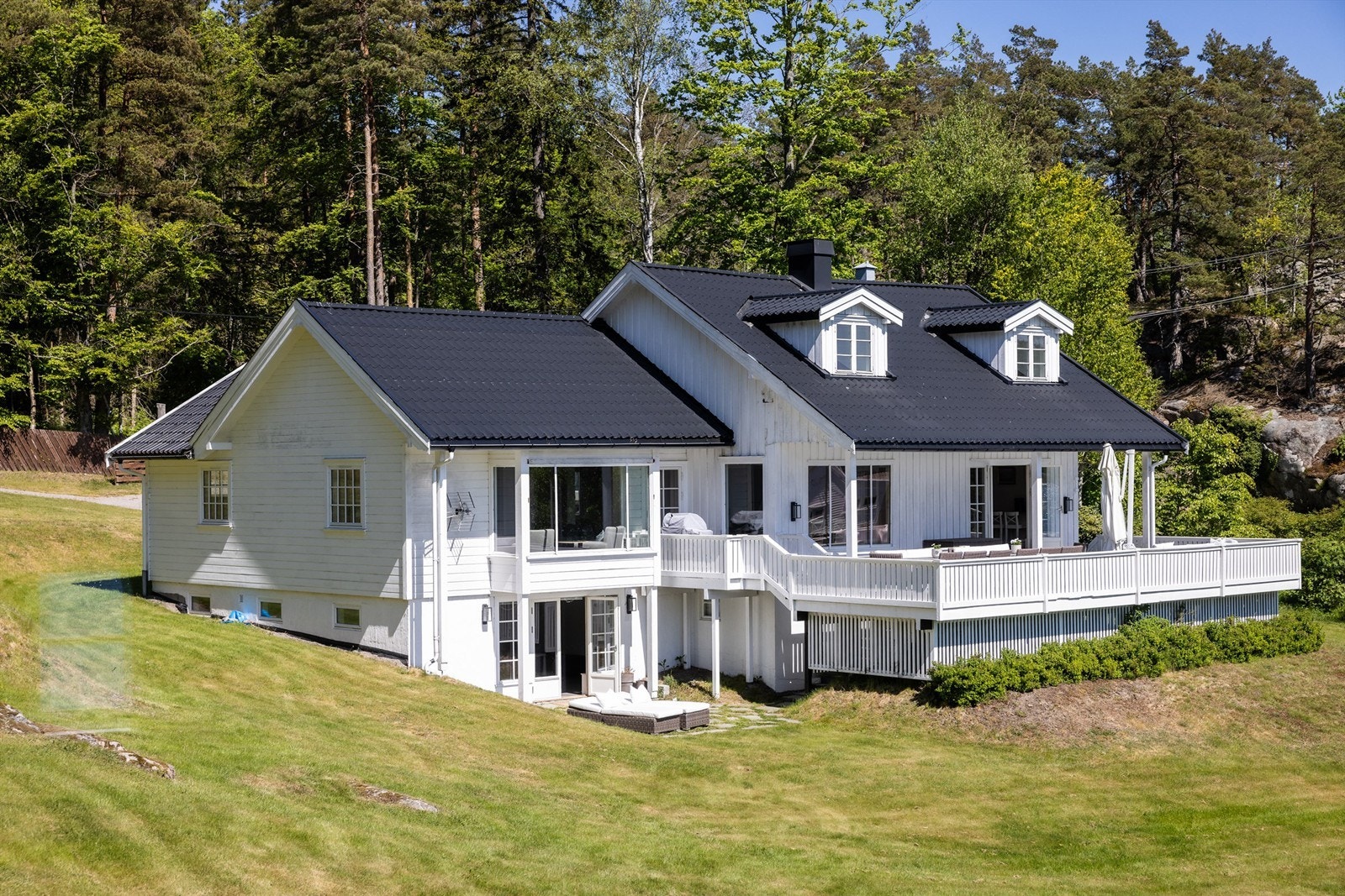 Hovedhuset sett fra siden, med store vindusflater mot sjøen. Galleribilde