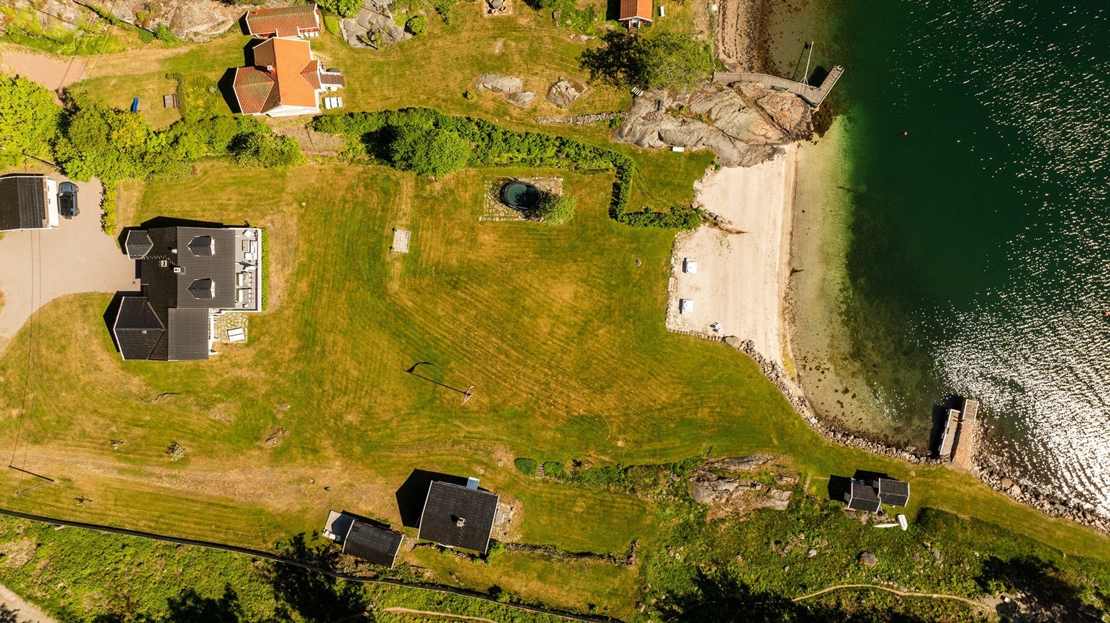 Tomten sett ovenfra, med strandlinje og bryggeanlegg. Galleribilde