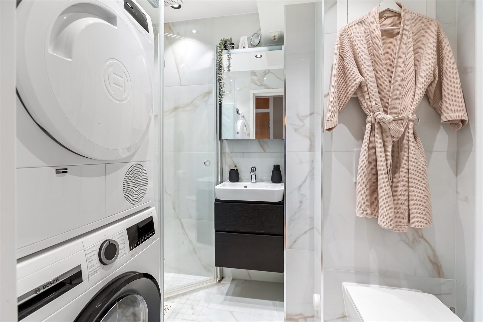 Badet er flislagt med store marmorinspirerte fliser på vegger og gulv, og har downlights i himlingen som gir behagelig belysning. Galleribilde