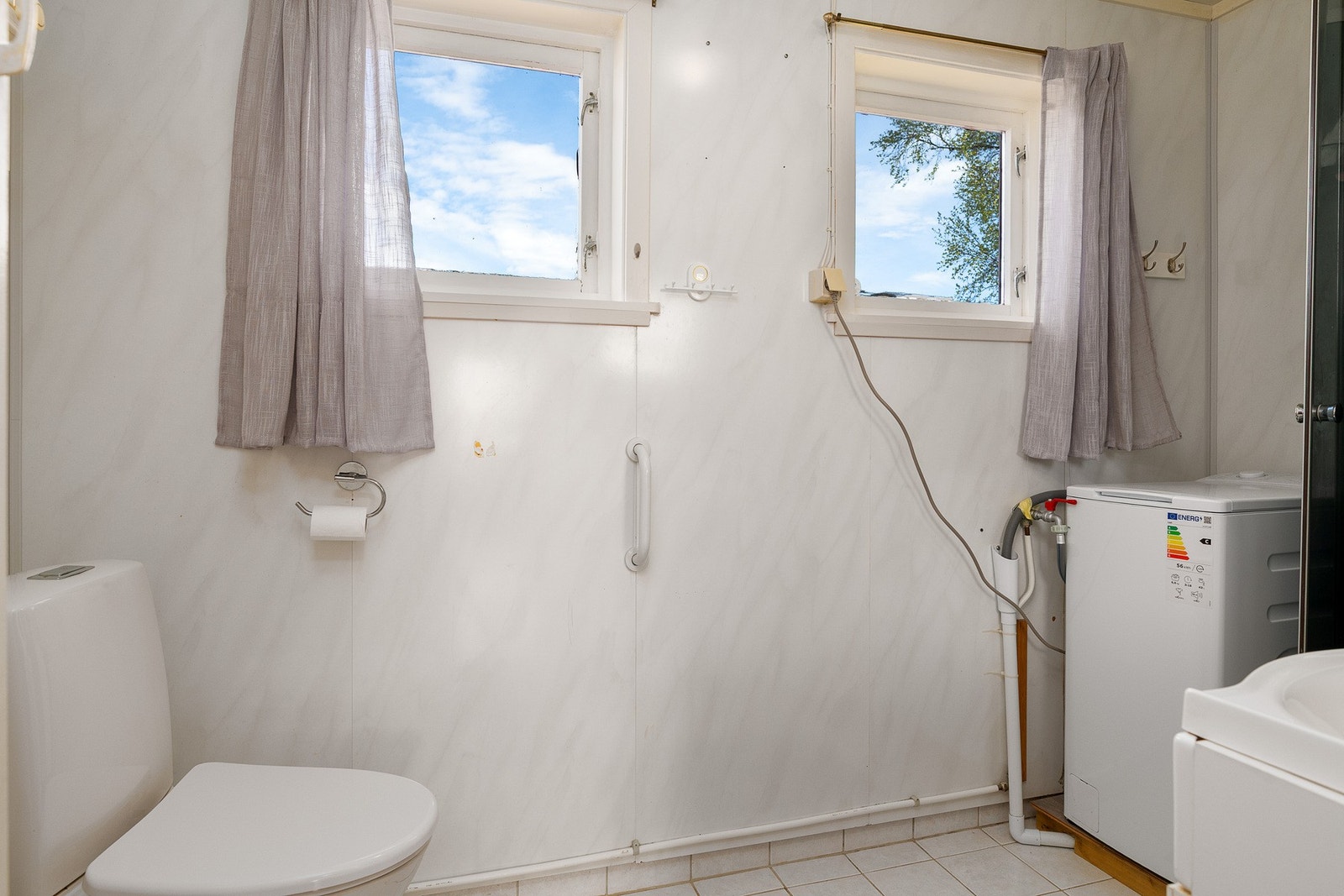 Bad med toalett og opplegg for vaskemaskin Galleribilde