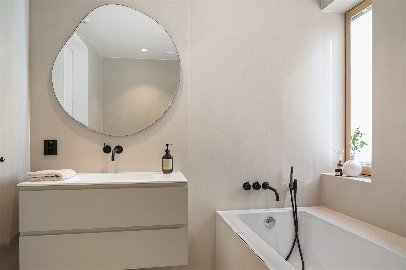 Også dette badet er delikat med store fliser og moderne, sorte armaturer Galleribilde