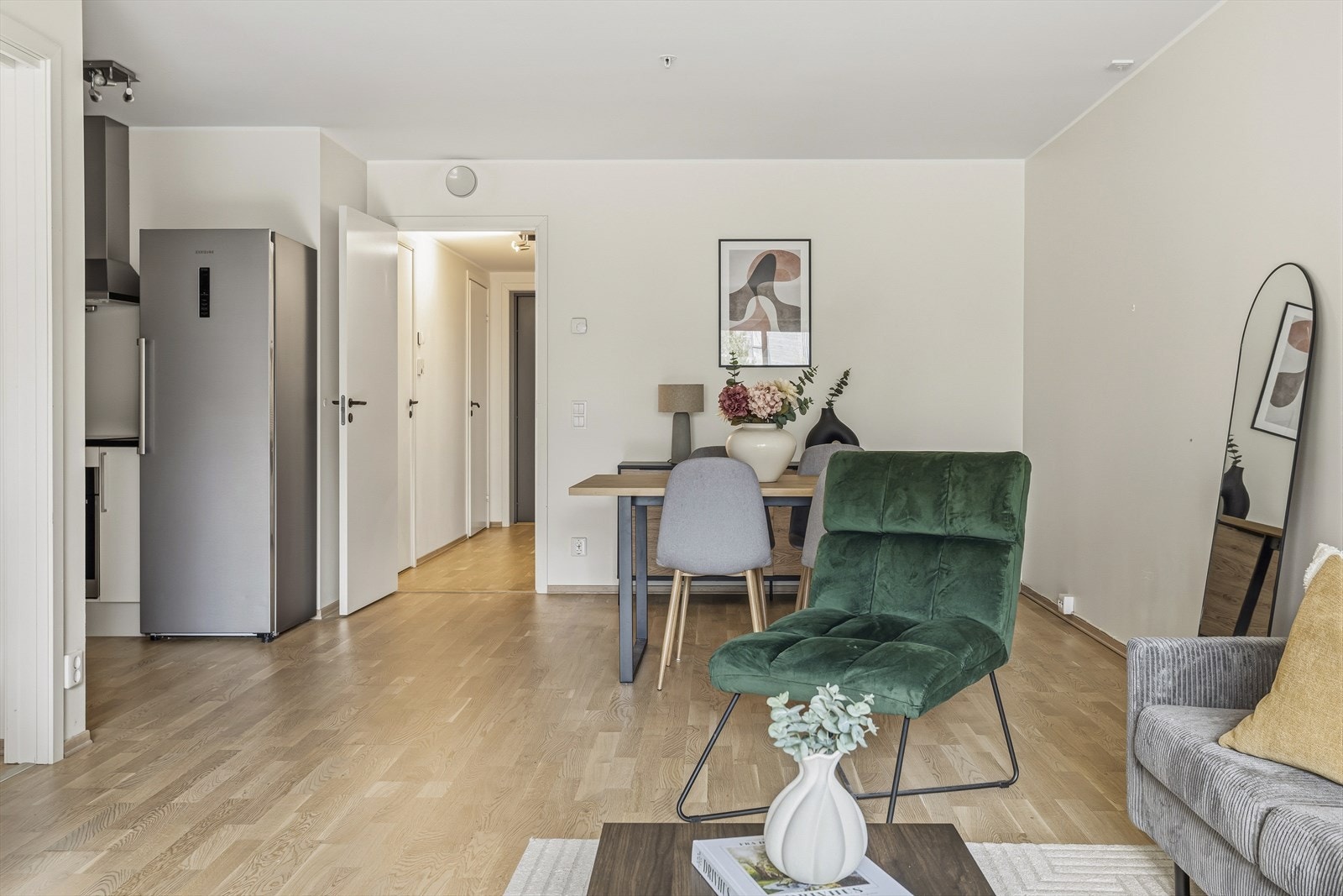 Gjennomgående materialvalg og lyse overflater skaper en helhetlig atmosfære. Kjøkkenet er integrert i oppholdsarealet og fremstår som praktisk og moderne med glatte fronter og plass til det du trenger i hverdagen. Galleribilde