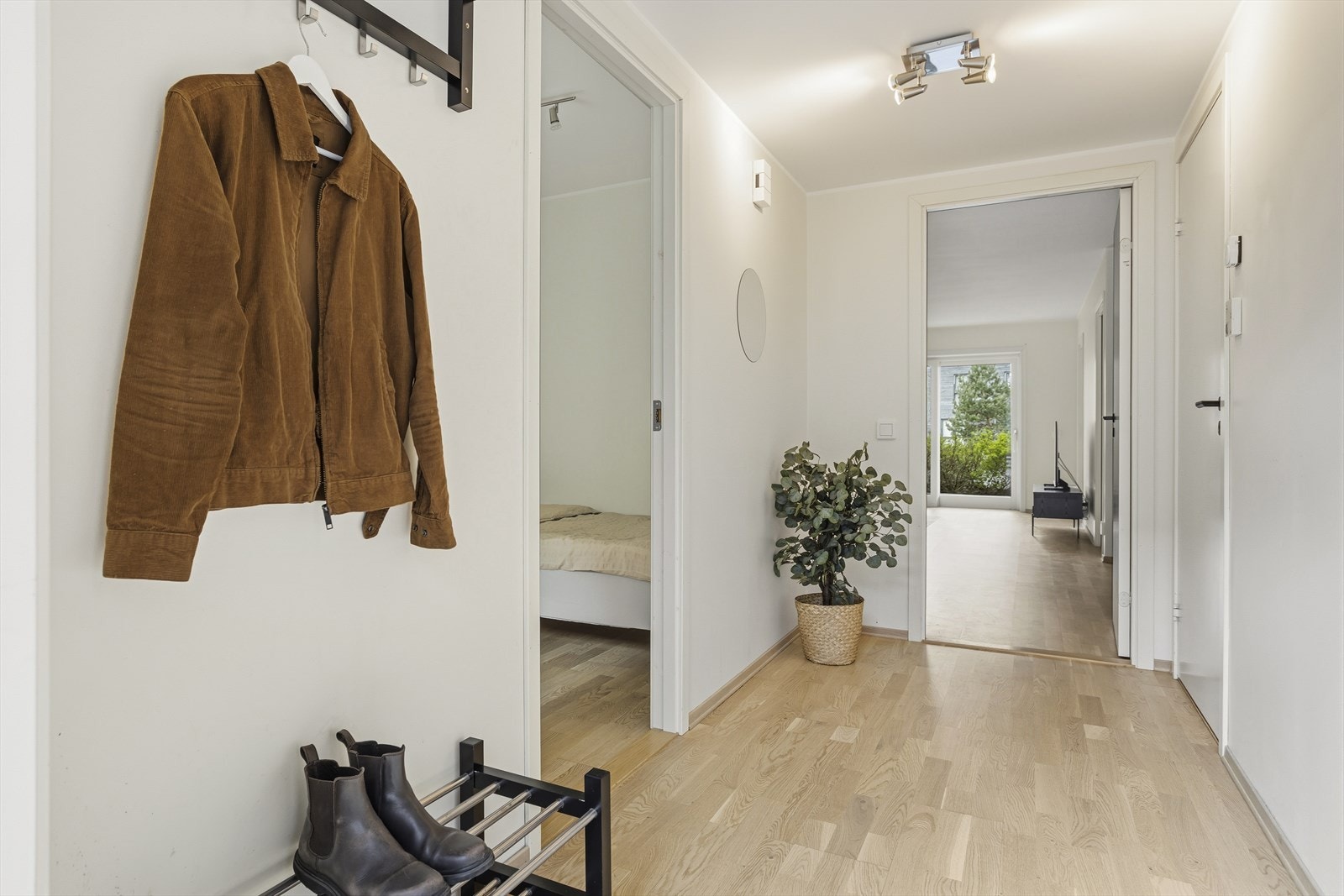 Ytterdøren leder inn til et areal med parkett på gulv og malte overflater, og herfra åpner leiligheten seg på en oversiktlig måte, oppholdsrommet rett frem mot terrassen, bad og ett soverom til høyre, samt det andre soverommet til venstre. Galleribilde