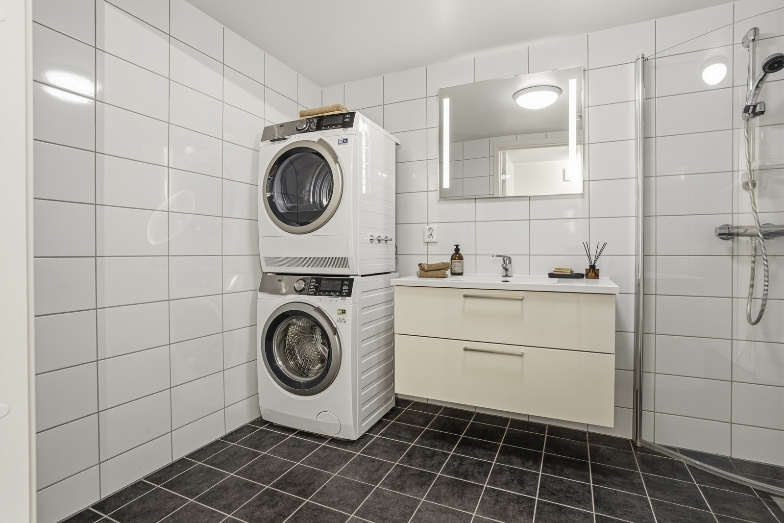 Rommet er utstyrt med dusjhjørne, vegghengt toalett med innebygd sisterne, samt servantinnredning med nedfelt servant og speil med integrert belysning. Det er behagelig gulvvarme, og opplegg for vaskemaskin er etablert. Galleribilde