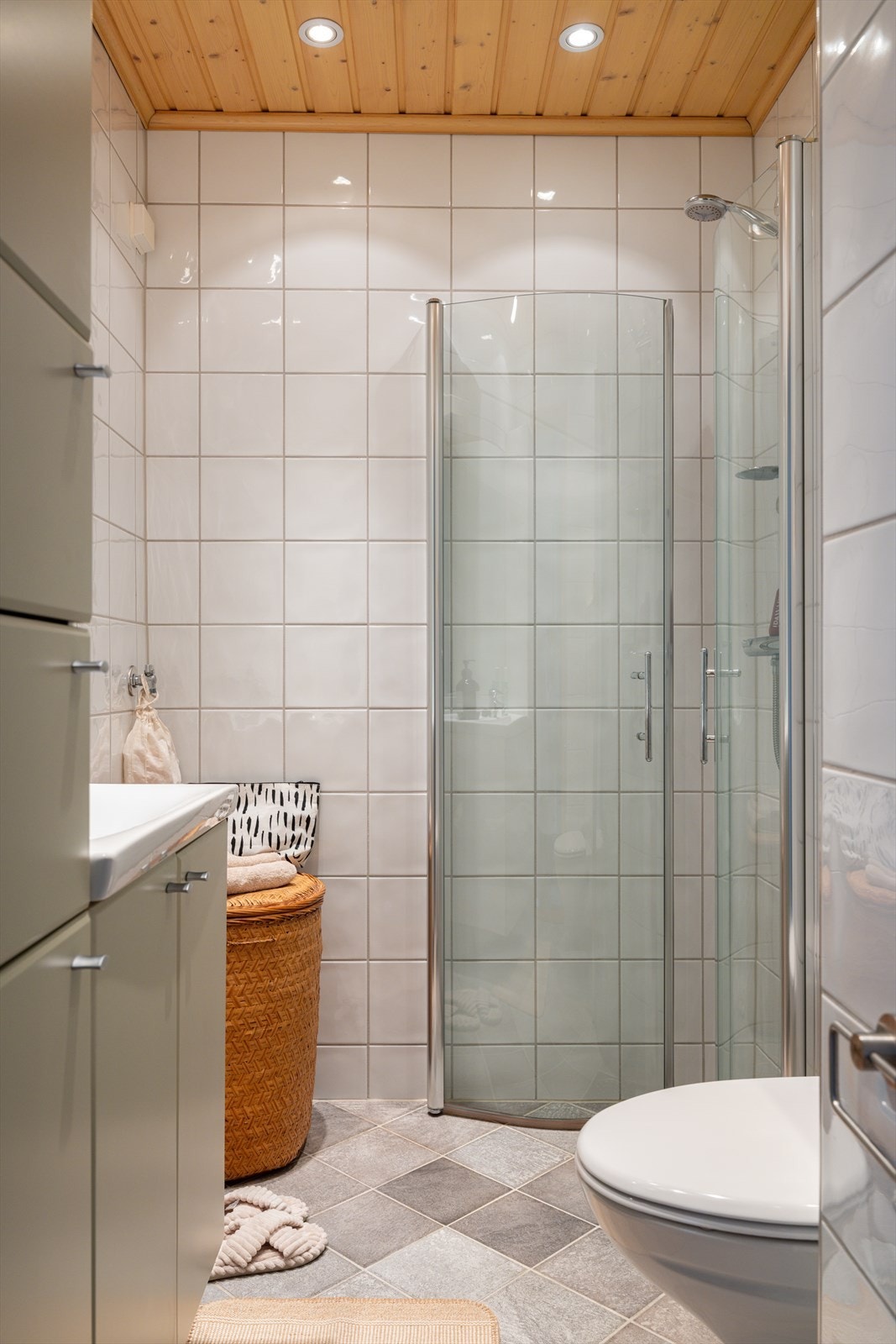 Pent flislagt baderom fra 2010. Badet er utstyrt med servant, veggmontert klosett og dusjhjørne med dusjing dirkete på flis. Galleribilde