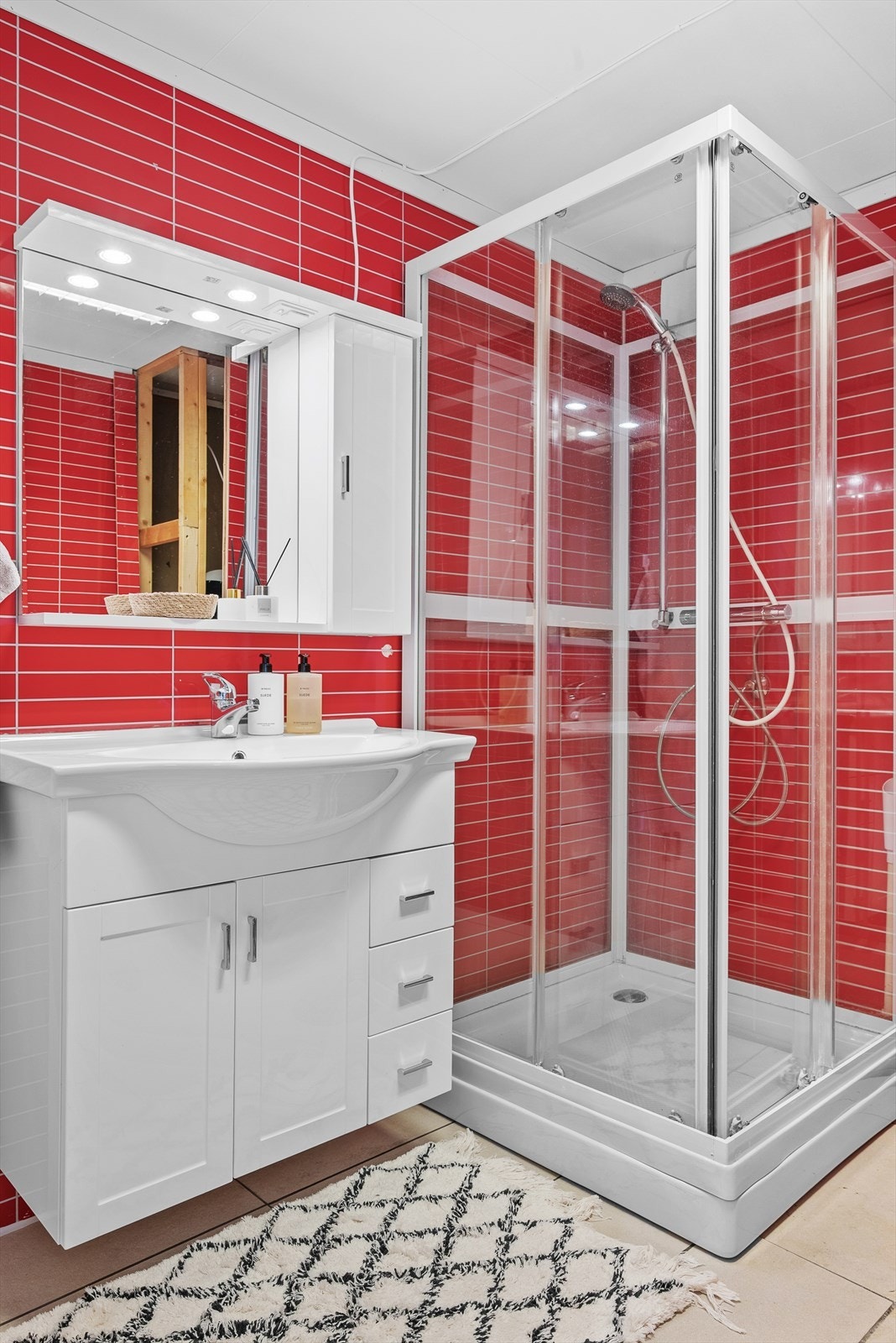 Badet i sokkeletasjen på 5,5 kvm har flislagt gulv med gulvvarme, flisplater på veggene , servantinnredning og dusjkabinett. Galleribilde