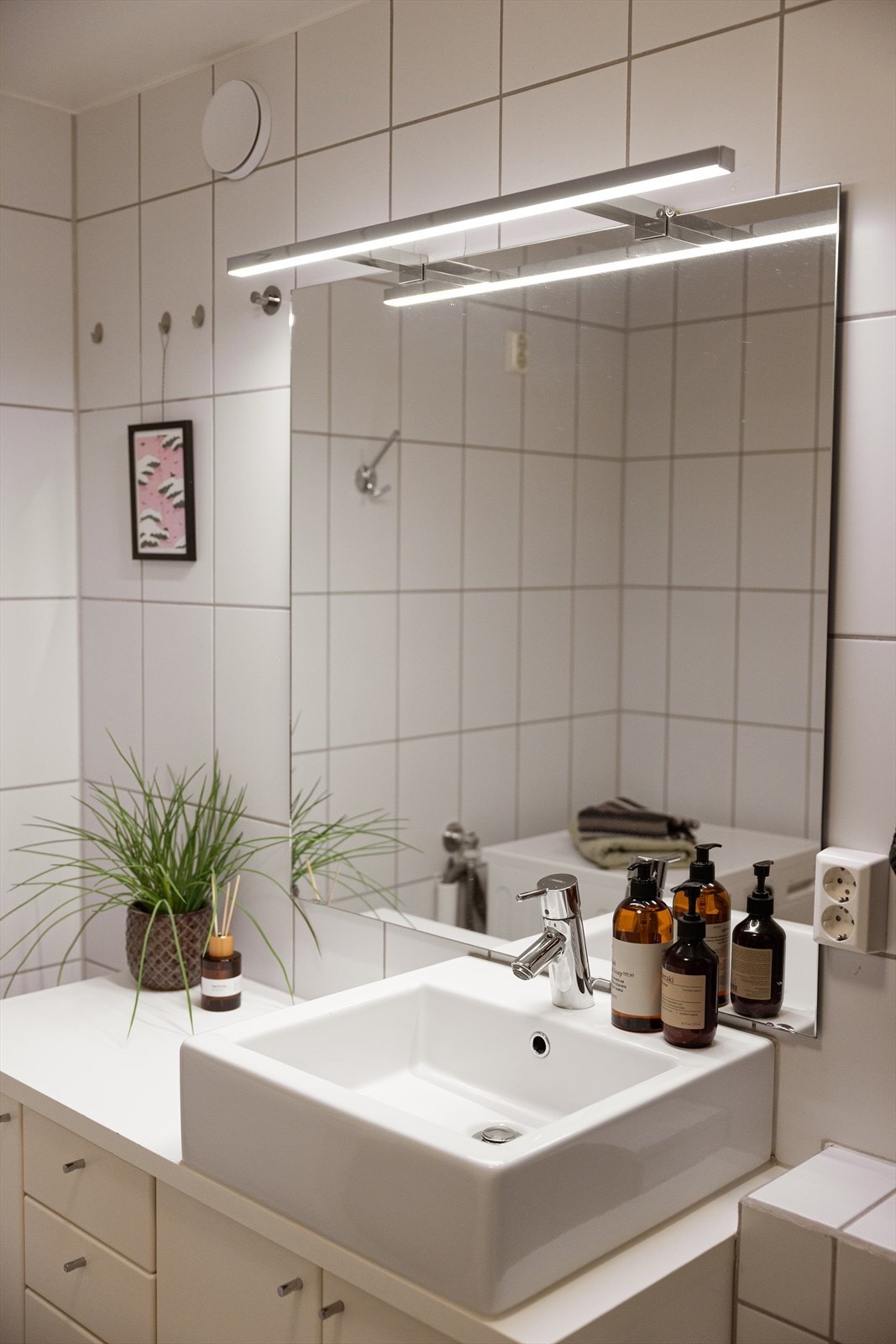 Baderomsinnredning med ovenpåliggende servant og speil med integrert belysning. Galleribilde