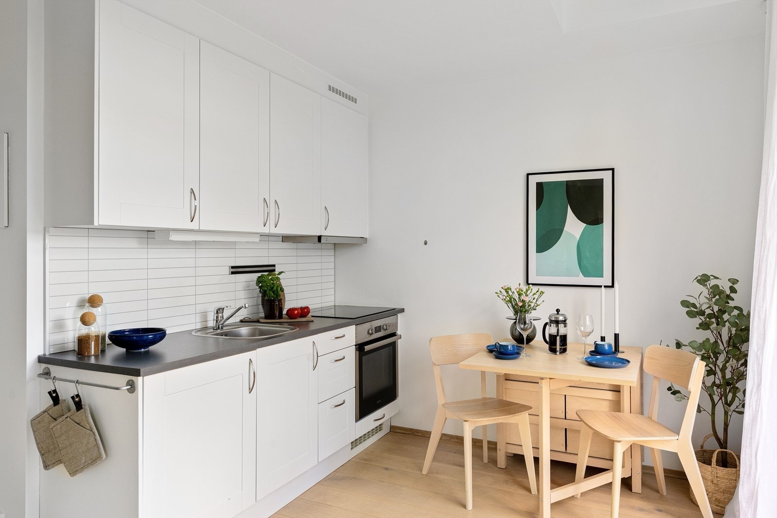 Moderne og stilrent kjøkken med glatte, laminerte fronter, laminat benkeplate og plater mellom overskap og benkeplate som gir et helhetlig uttrykk. Galleribilde