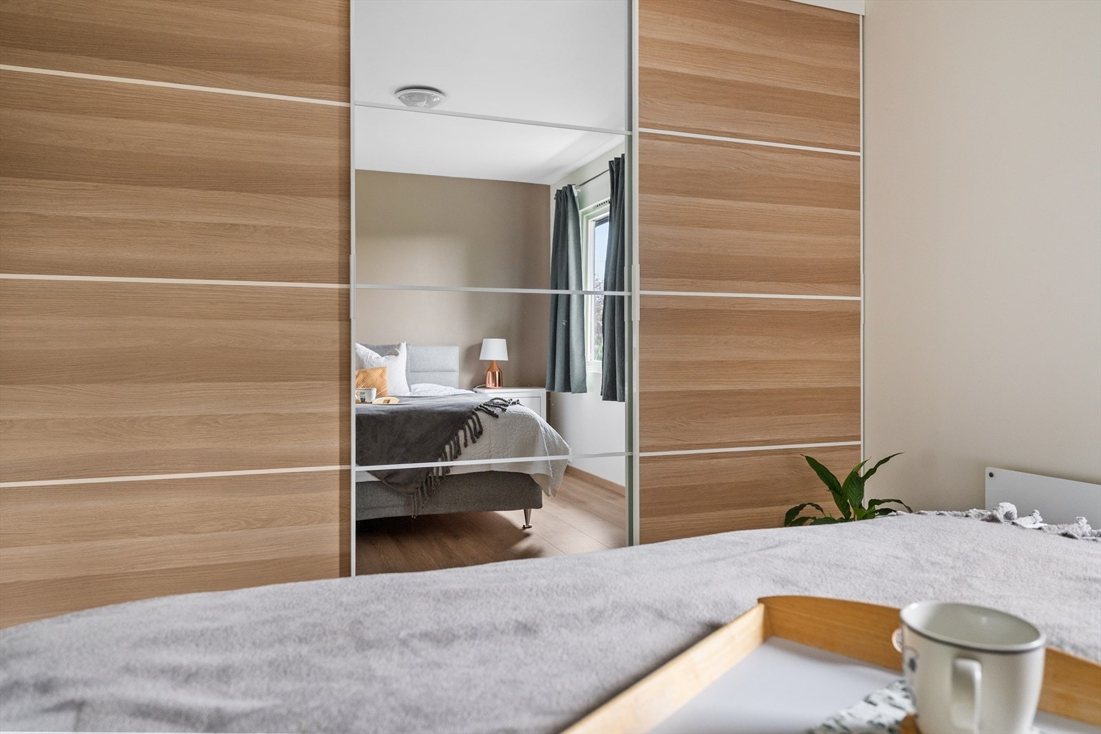 Rommet har god plass til ønsket møblering og er utstyrt med en stor skyvedørsgarderobe som gir rikelig med praktisk oppbevaringsplass samtidig som den bidrar til et stilrent uttrykk. Galleribilde