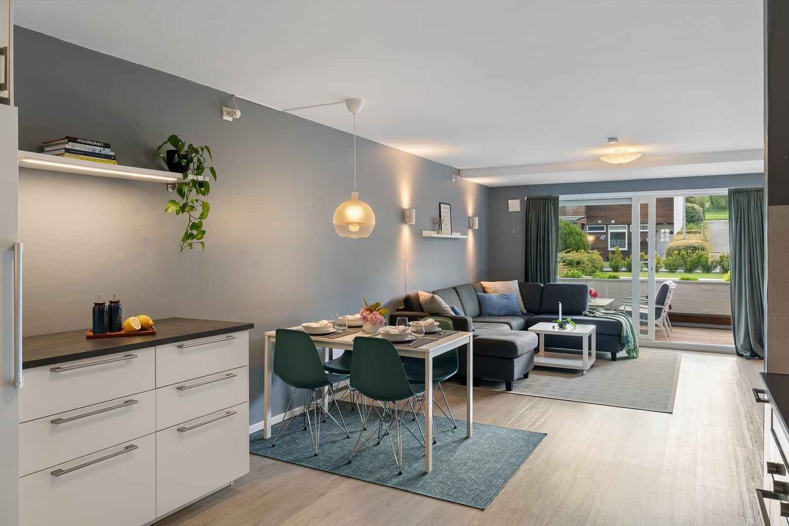 Stue og kjøkken med i åpen løsning, med spiseplass, store vindusflater og utgang til terrasse og hage. Galleribilde