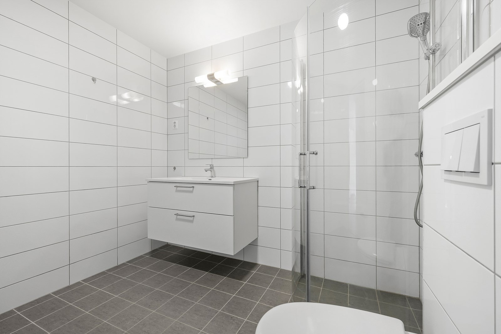 Badet er utstyrt med baderomsmøbel med heldekkende servant, dusjhjørne, veggmontert toalett og opplegg for vaskemaskin. Galleribilde