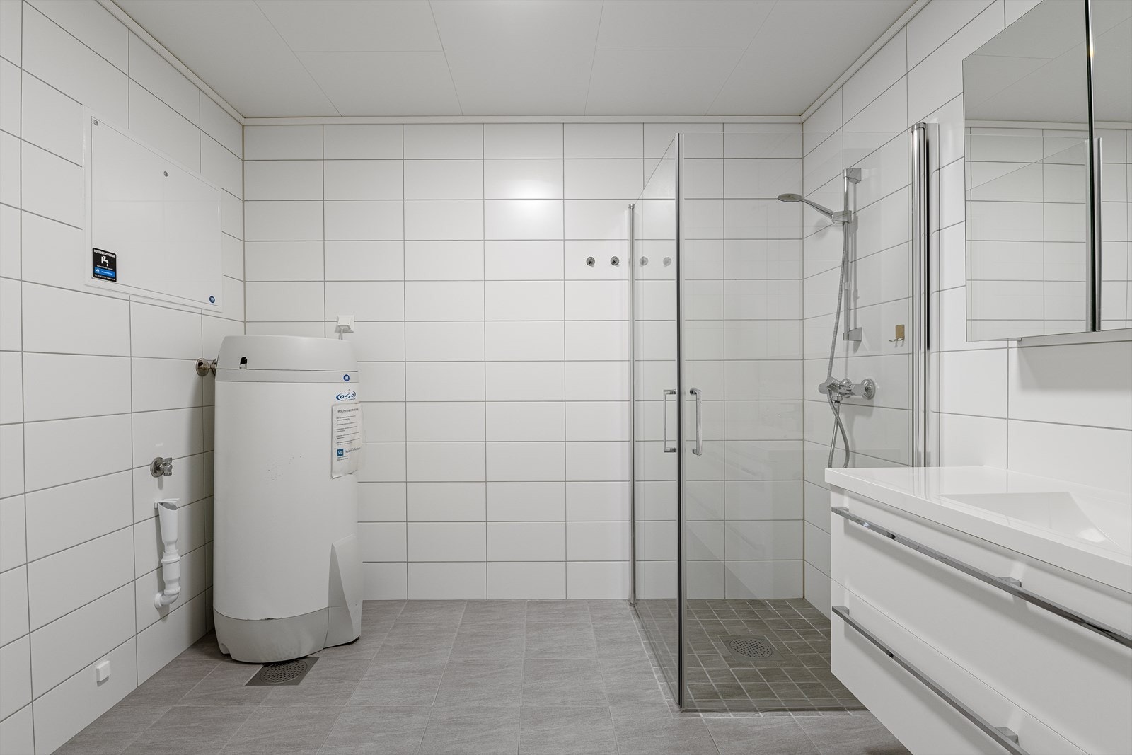 Badet er kombinert vaskerom med opplegg for vaskemaskin. Her er også varmtvannstank og fordelerskap for rør-i-rør-systemet plassert. Galleribilde