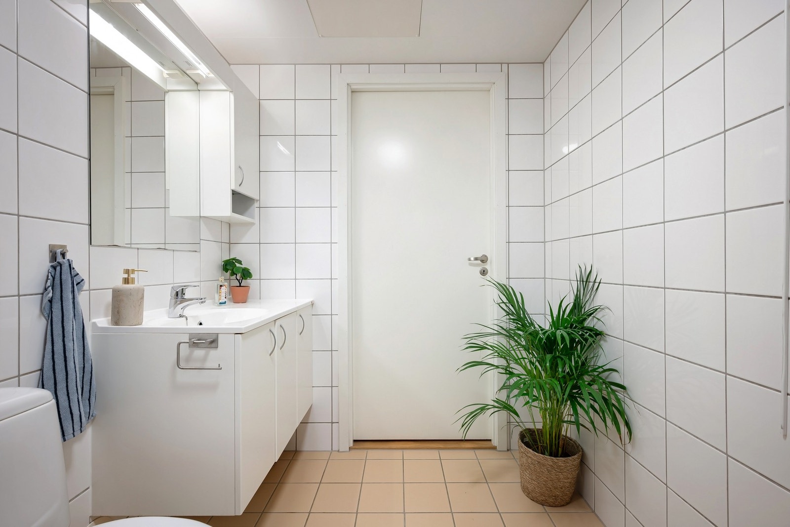 Badet er innredet med servantskap med glatte fronter og heldekkende servant, samt speil med lysarmatur over servant. Galleribilde