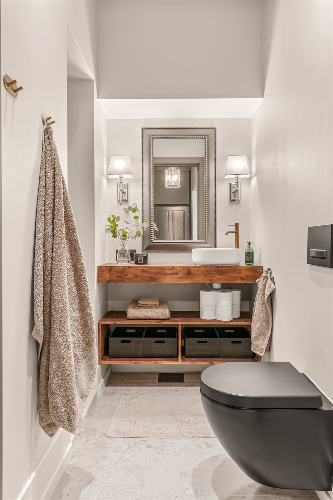 Badet fremstår moderne og delikat med et stilrent uttrykk og gjennomførte materialvalg. En lekker servant plassert på en solid benkeplate i tre tilfører varme til rommet og skaper en fin kontrast til de lyse overflatene. Galleribilde